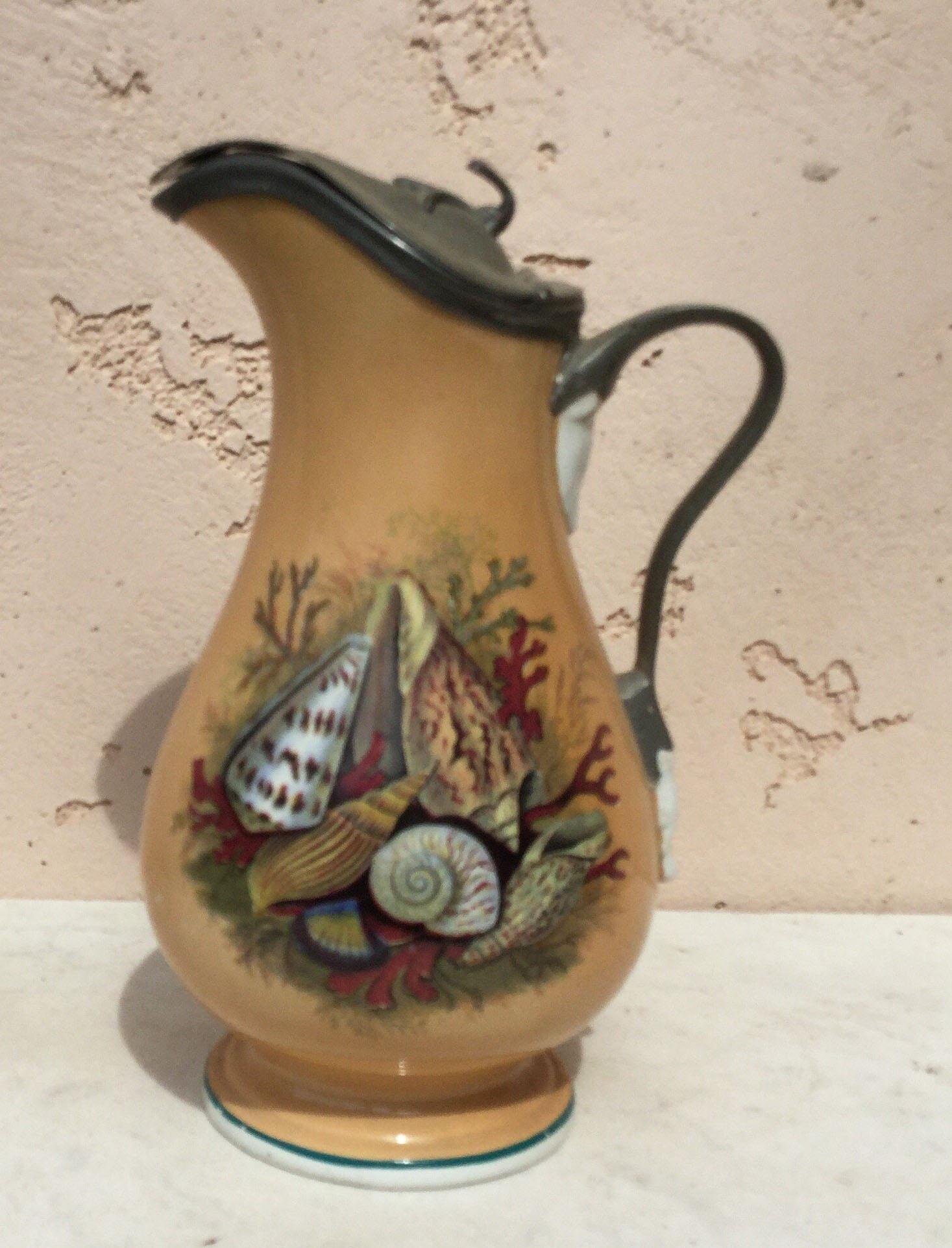 Antique English pitcher with seashells, seaweeds and coral with a metal lid.
