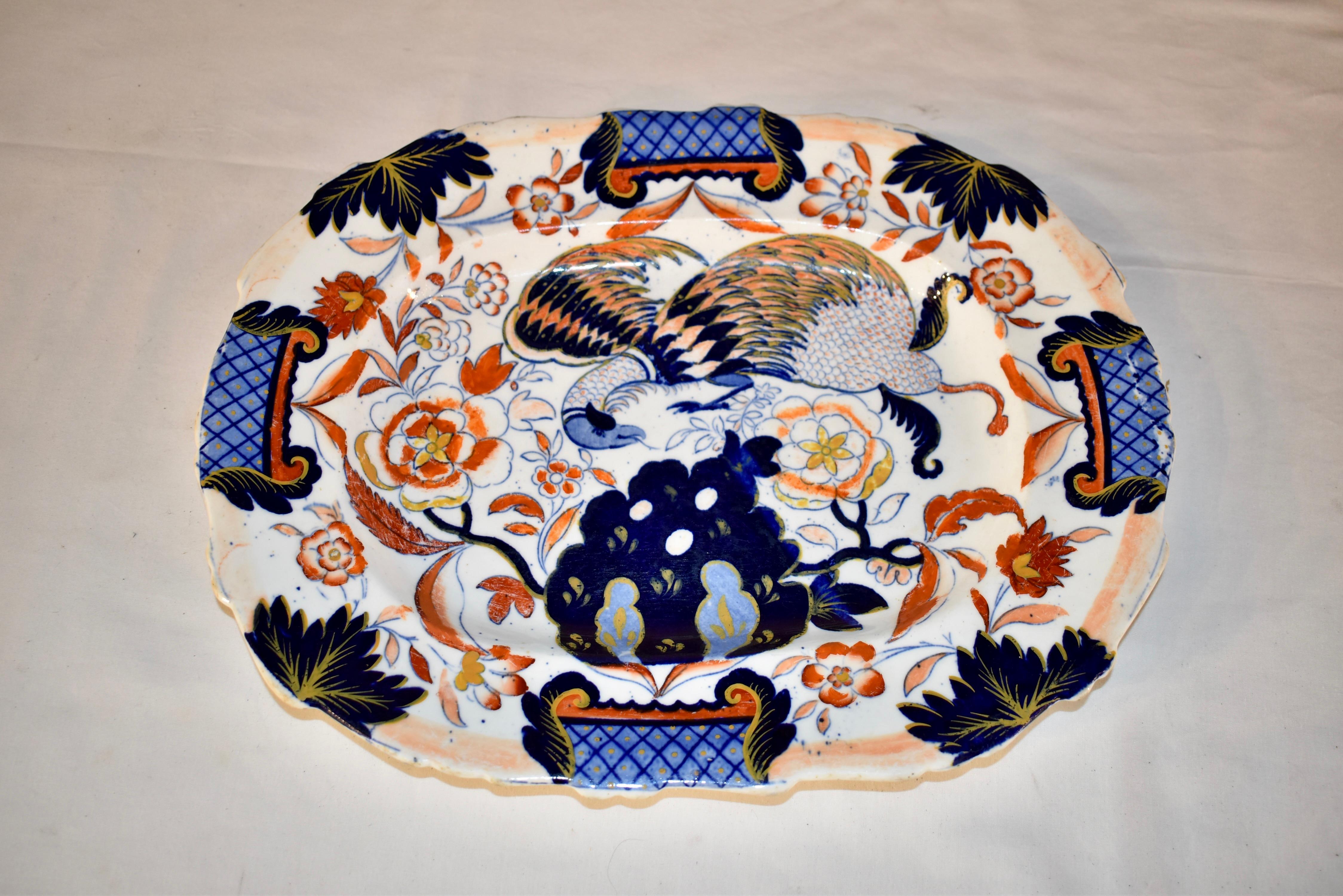 Plat en porcelaine anglaise du XIXe siècle avec une belle décoration peinte à la main et par transfert. Le motif représente un phénix parmi une multitude de fleurs avec des jardinières sur les quatre côtés du plat.