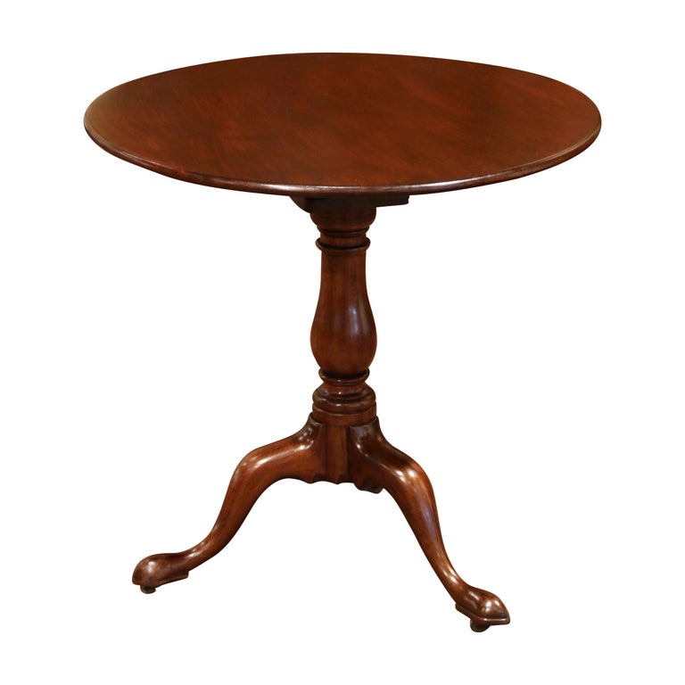 This elegant antique tea table was crafted in England circa 1860; made of mahogany, the table stands on a three-leg pedestal base over a carved turned stem. The round top tilting mechanism is secured underneath with a brass lock. The tea table is in