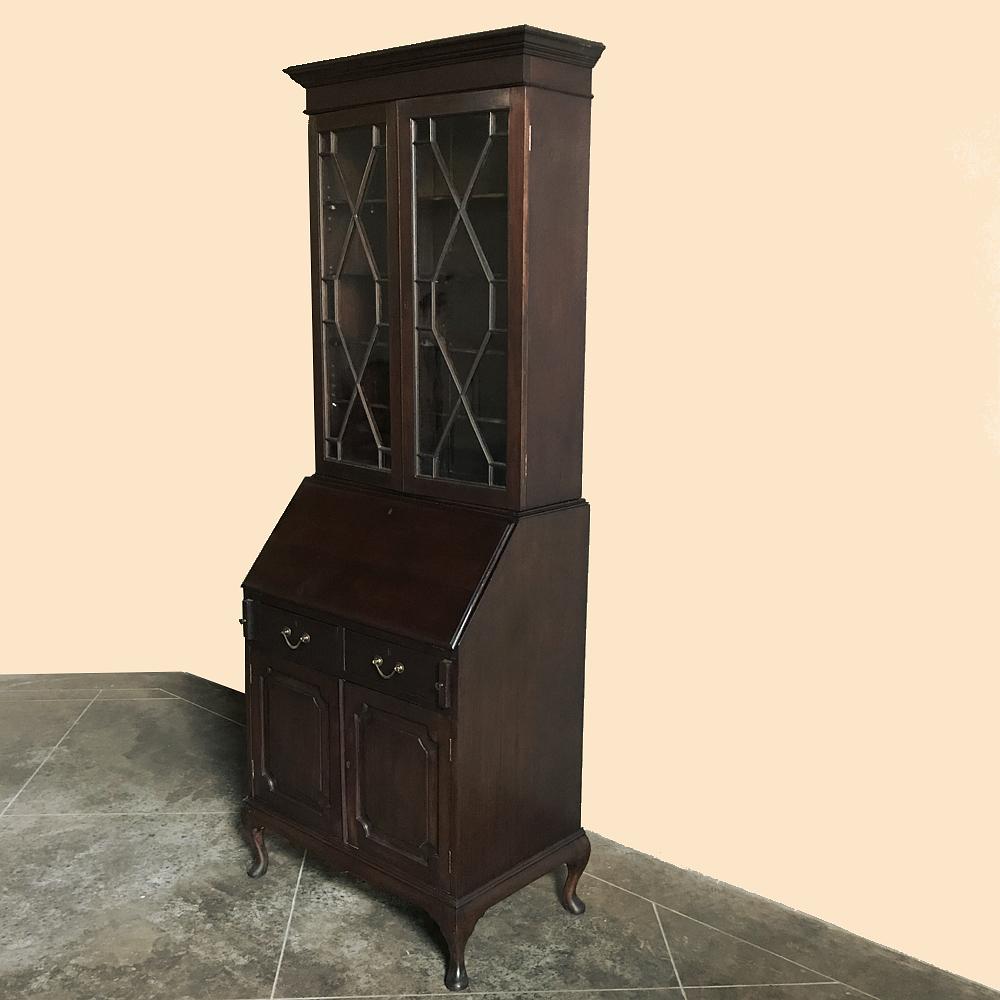 The essence of tailored functionality, this stately Antique English Secretary ~ Bookcase was hand-crafted from fine imported Mahogany, then fitted with brass drawer pulls and key guards and scrolled feet in the timeless Queen Anne style. Drop front