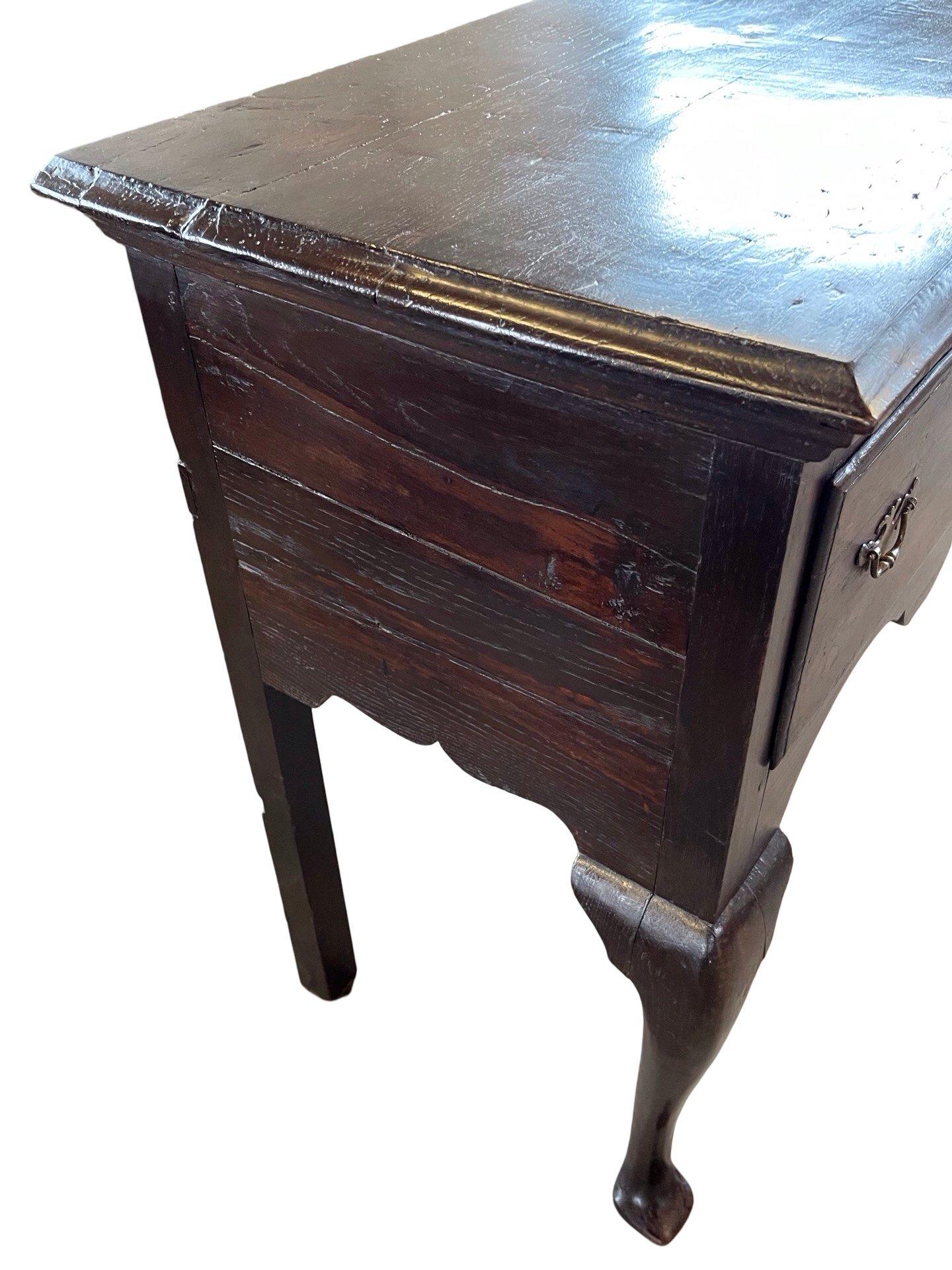 Queen Anne console table hand-made in England in the early 1800s using oak and pegged construction. The table has a beautiful color and patina and features two overlay drawers with ogee edges. The drawers show beautiful hand-made dovetail joints and