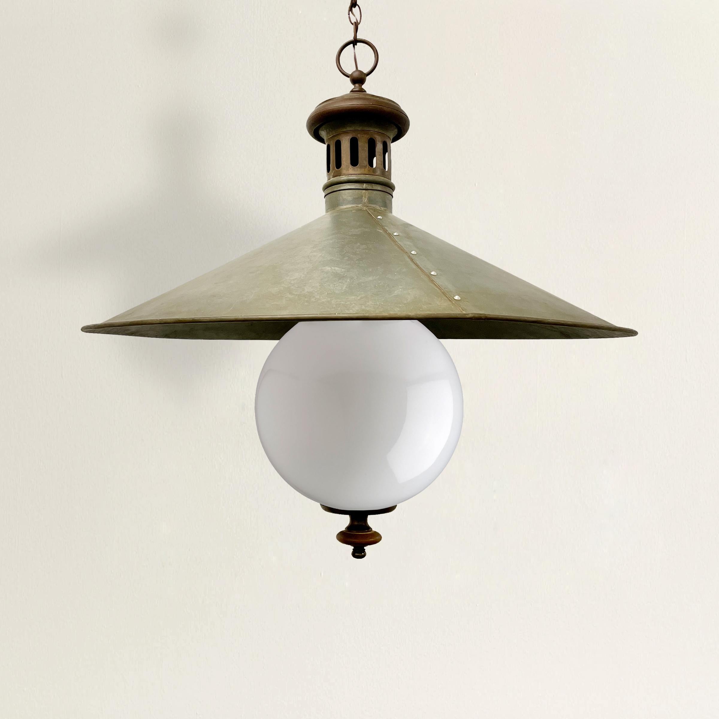 A beautiful and striking 19th century English railroad light fixture with a large round conical zinc shade, copper fittings, and a large opaque white glass shade. This fixture originally would have used gas, but it has been retrofitted for