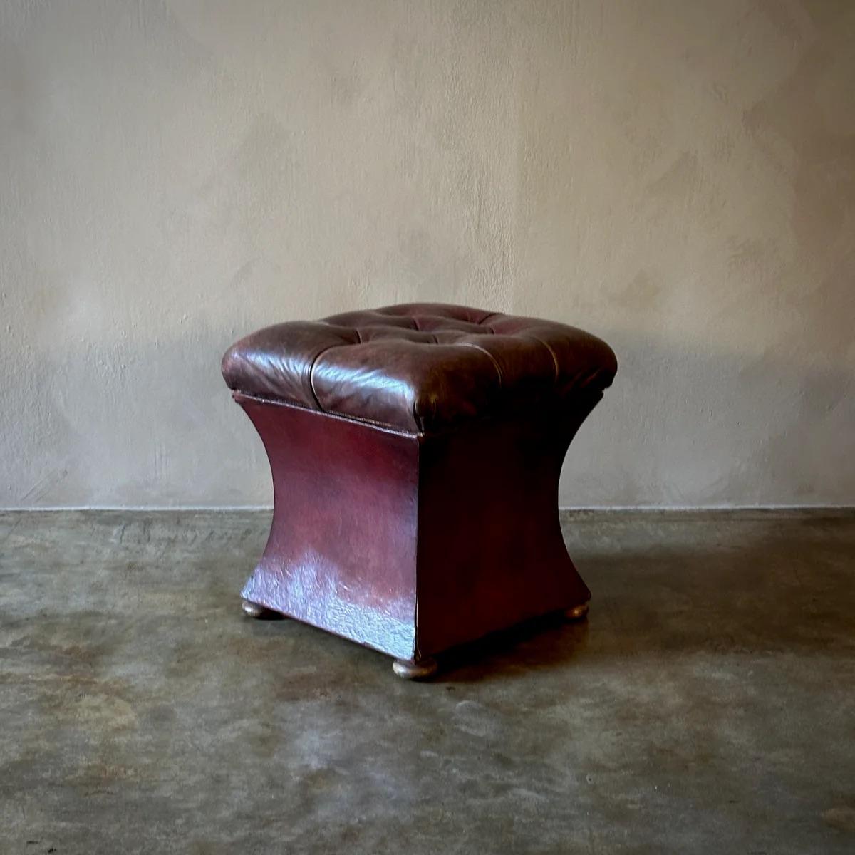 Dieser englische Ottoman ist mit reichem, rotem Leder gepolstert und zeigt ein hübsches getuftetes Design. Der abnehmbare Sitz lässt sich anheben und gibt ein diskretes Staufach frei, das seine Funktionalität noch erhöht. Die Ottomane wird von