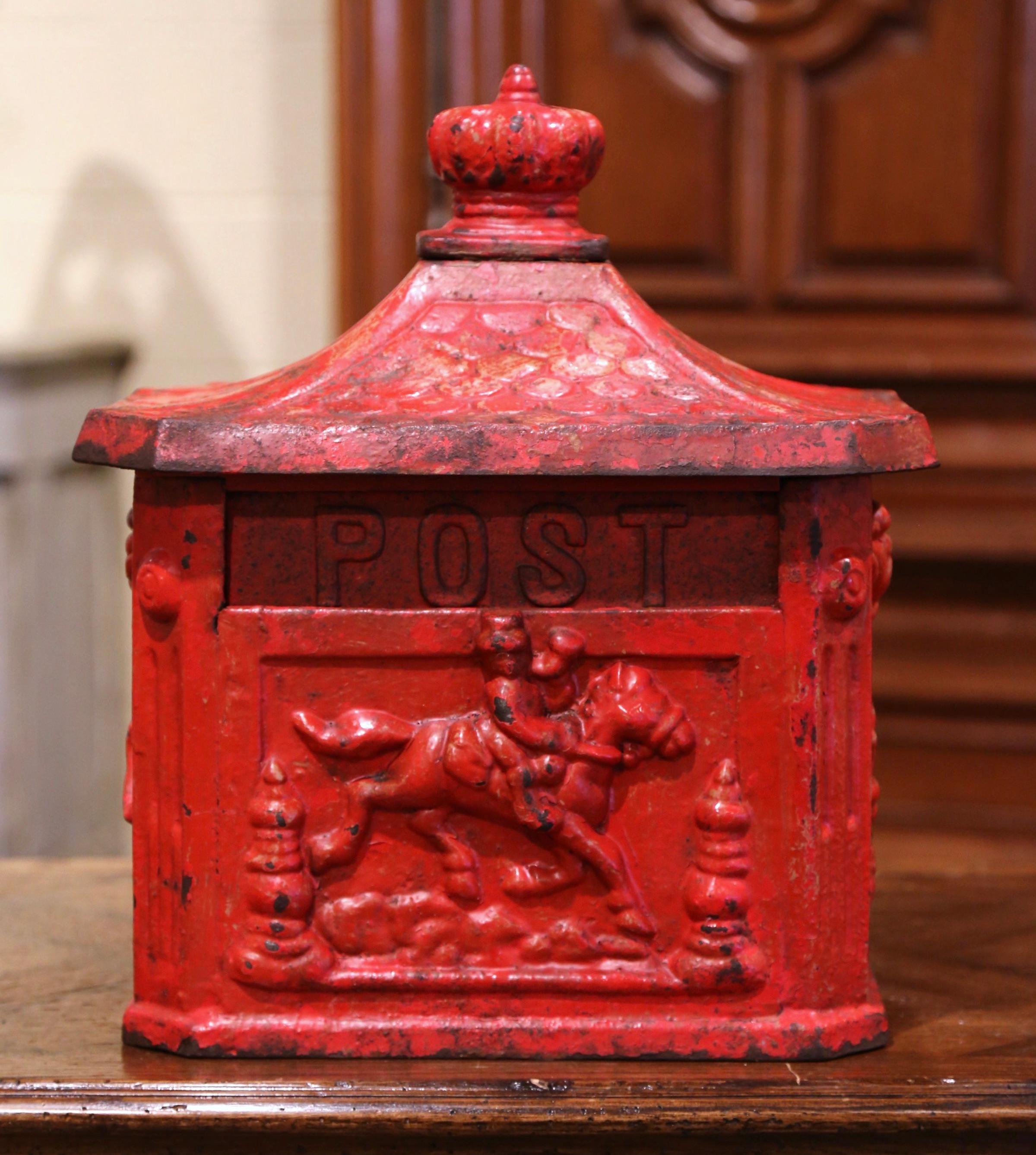 This antique iron mailbox was forged in England, circa 1880. The mail holder features high reliefs decorations on all four sides, including a pastoral scene and a horseman on the opposite side. The front has a letter slot with word 
