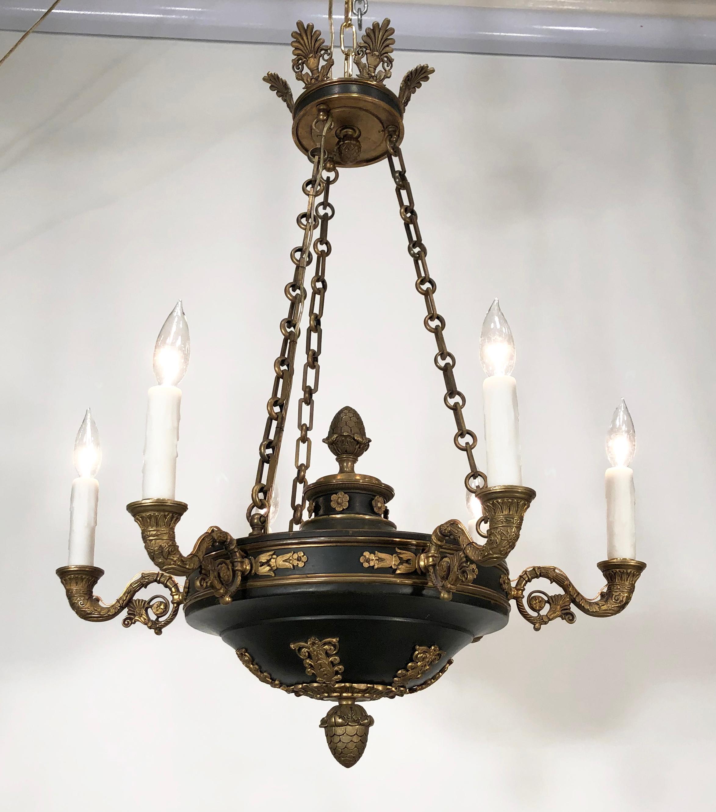 This beautiful 1820s-1830s English Regency bronze chandelier has an Egyptian motif. This amazing chandelier has six bronze arms mounted to a patinated bowl that is suspended by 3 bronze chains from a Regency Crown with Anthemion’s. Decorative pine