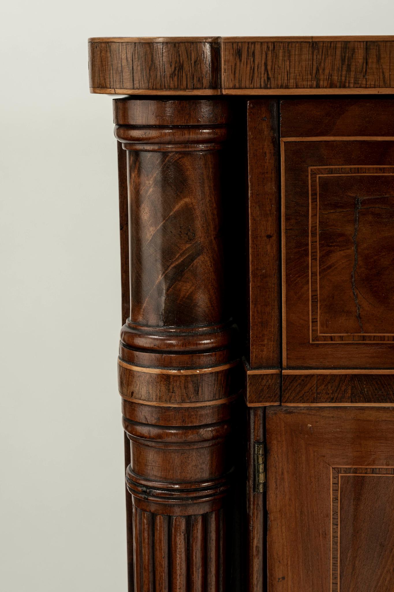 A long and stately 19th century English server with mixed wood inlays featuring two cabinet doors and keyed drawer.
