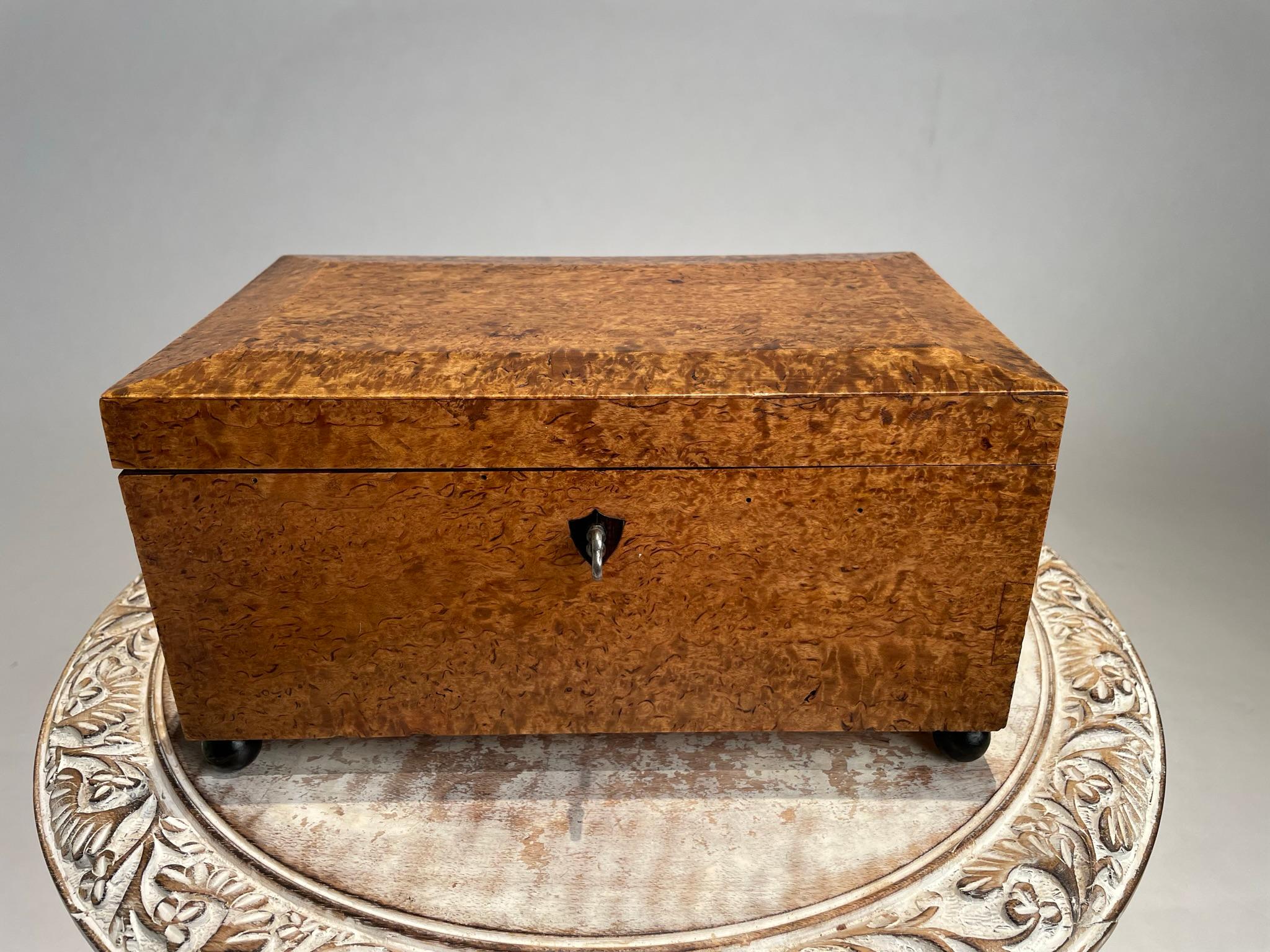 A handsome and beautifully made English Regency burl wood veneered box. The thick burl veneer covering the four sides and top, resting on four ebonized ball feet . A rich honey patina that only comes with age and handling. Inset ebony escutcheon,