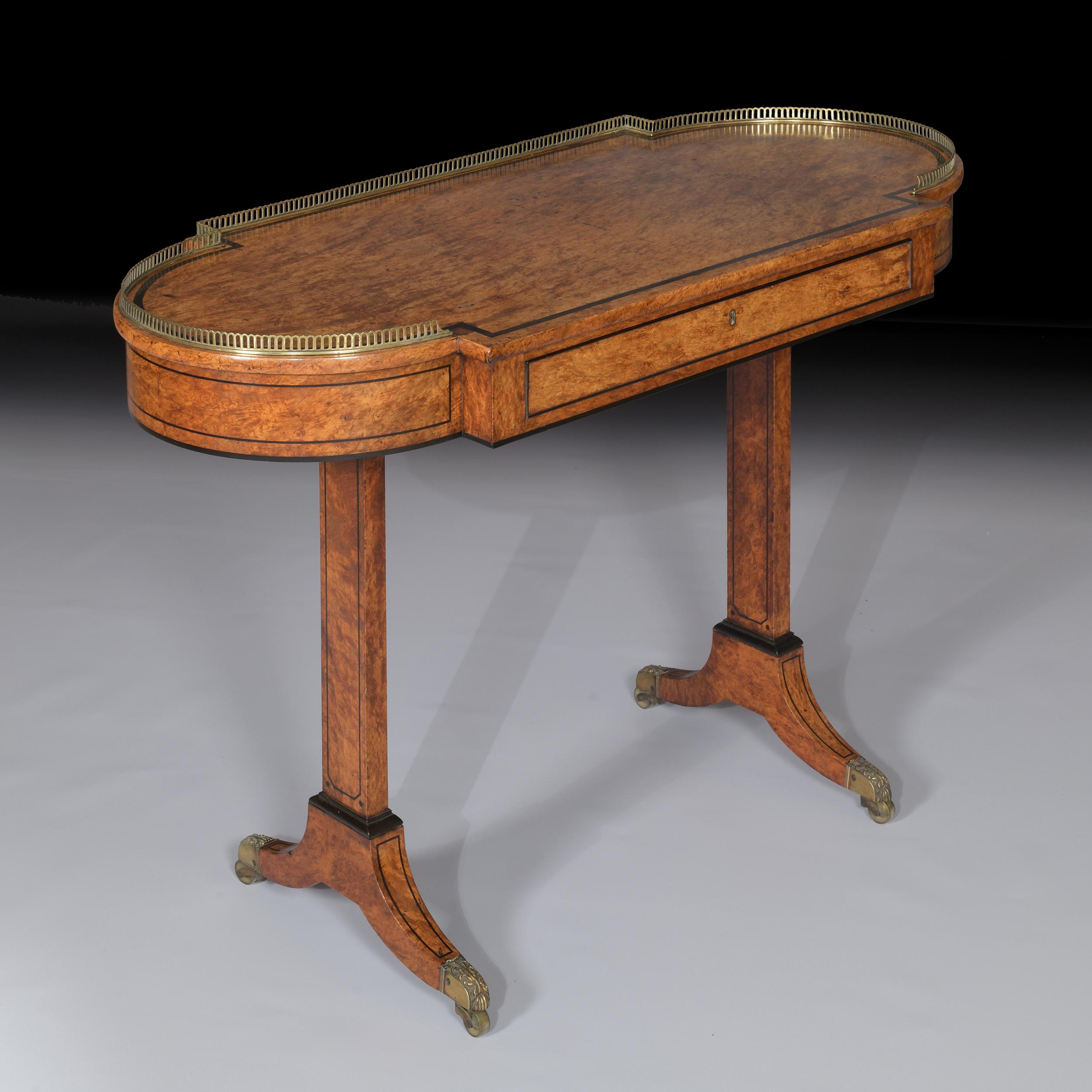A fine Regency burr elm and ebony strung writing table,the top with bowed ends and a brass three-quarter gallery, the frieze drawer with ebony cockbeading, raised on trestle end supports ending in sabre legs with brass cappings and castors.

Circa