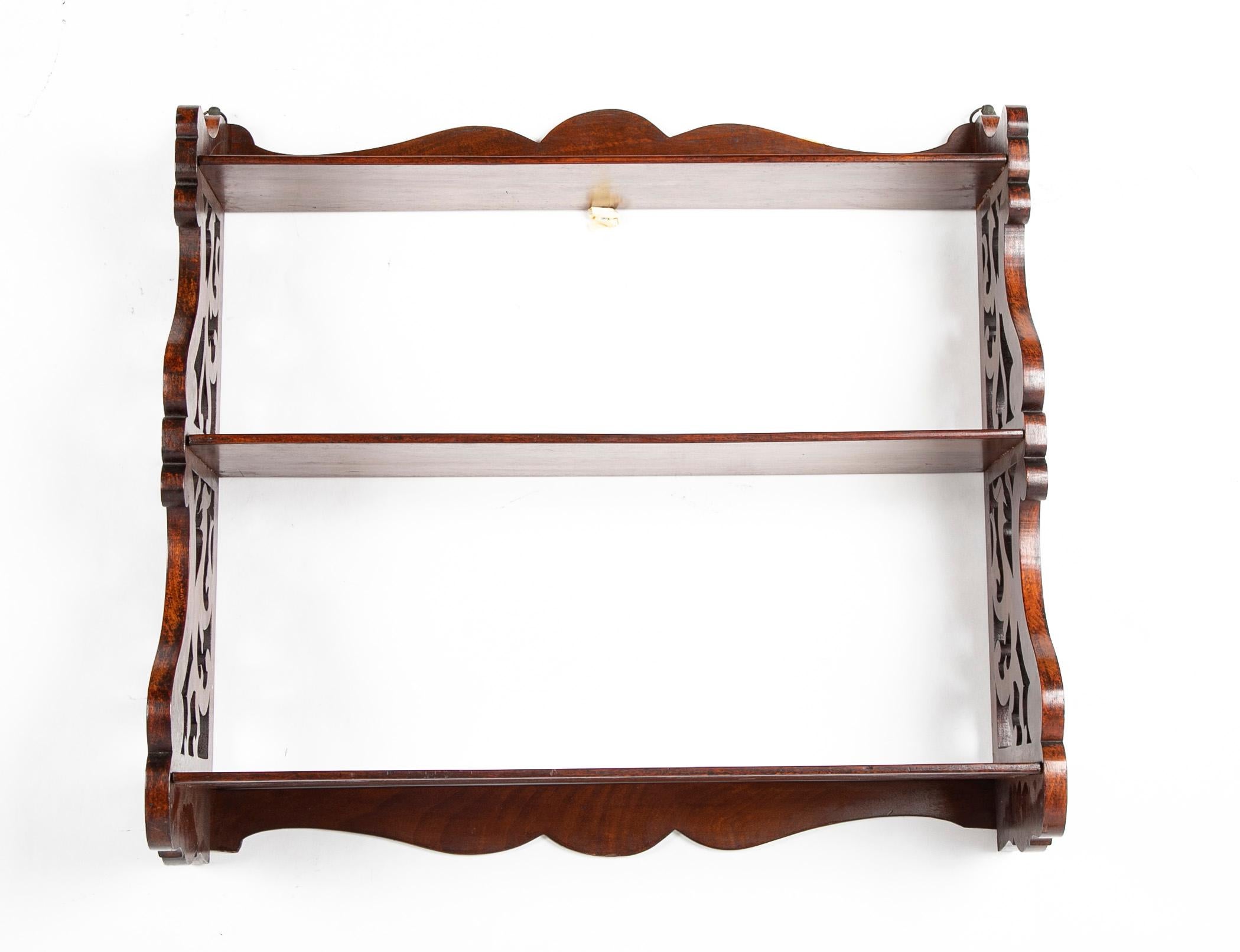 19th Century English Regency mahogany hanging shelf with three tiers supported by carved fretwork sides depicting stylized birds. A handsome and sturdy addition to your den as a bookshelf, pantry, kitchen or anyplace a small useful shelf would be