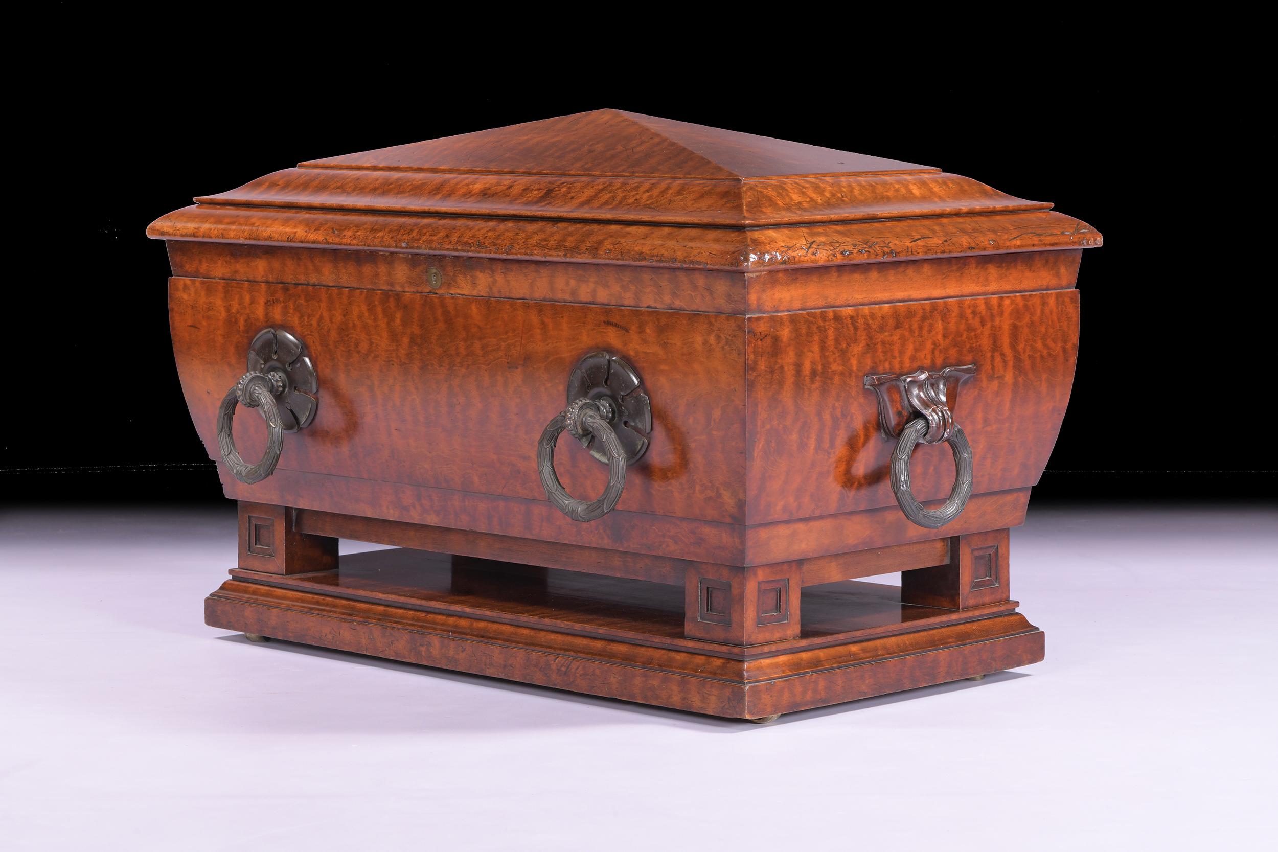 A magnificent Regency plum mahogany wine cooler attributed to George Bullock., of sarcophagus form, hinged lid above a partitioned lead-lined interior with applied bold bronze ring handles, raised on plinth base.

Circa 1820

English

Artist