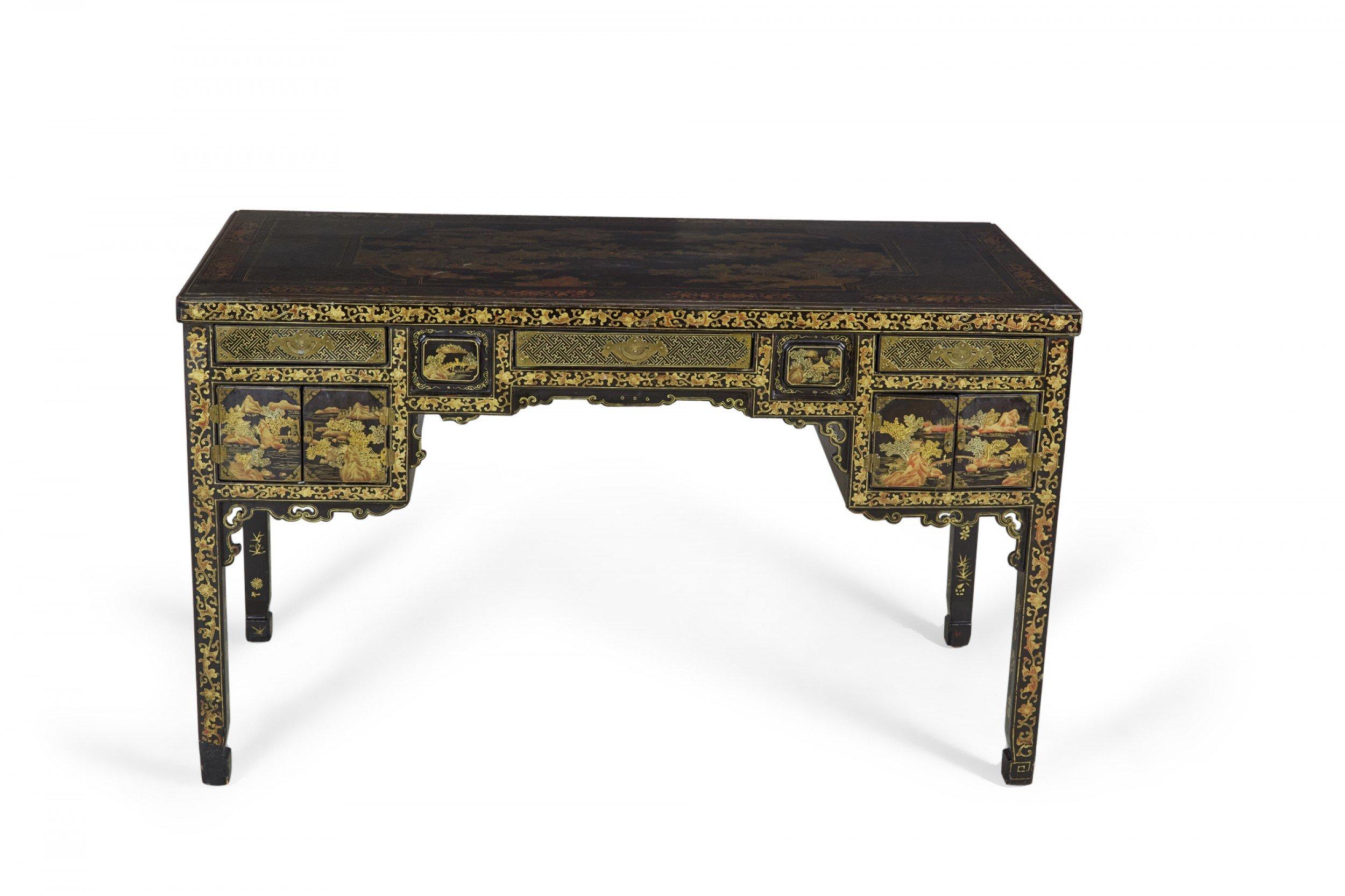 English Regency Chinese export (19th Century) black lacquer desk with foliate trim and Chinese landscape imagery in gilt throughout with 3 frieze drawers over a kneehole flanking 2 double hinged doors all with bronze pulls.
  