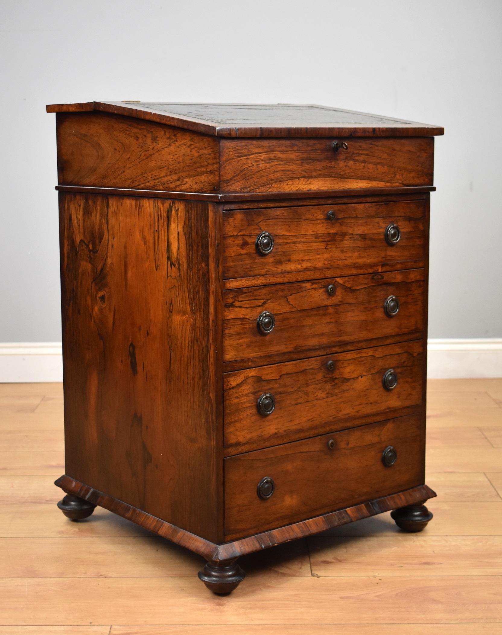 A good quality Regency rosewood davenport, the top inset with an antique leather, opening to reveal storage space and a single drawer. Below this there are four graduated drawers, each with brass handles and escutcheons. One side has dummy drawers