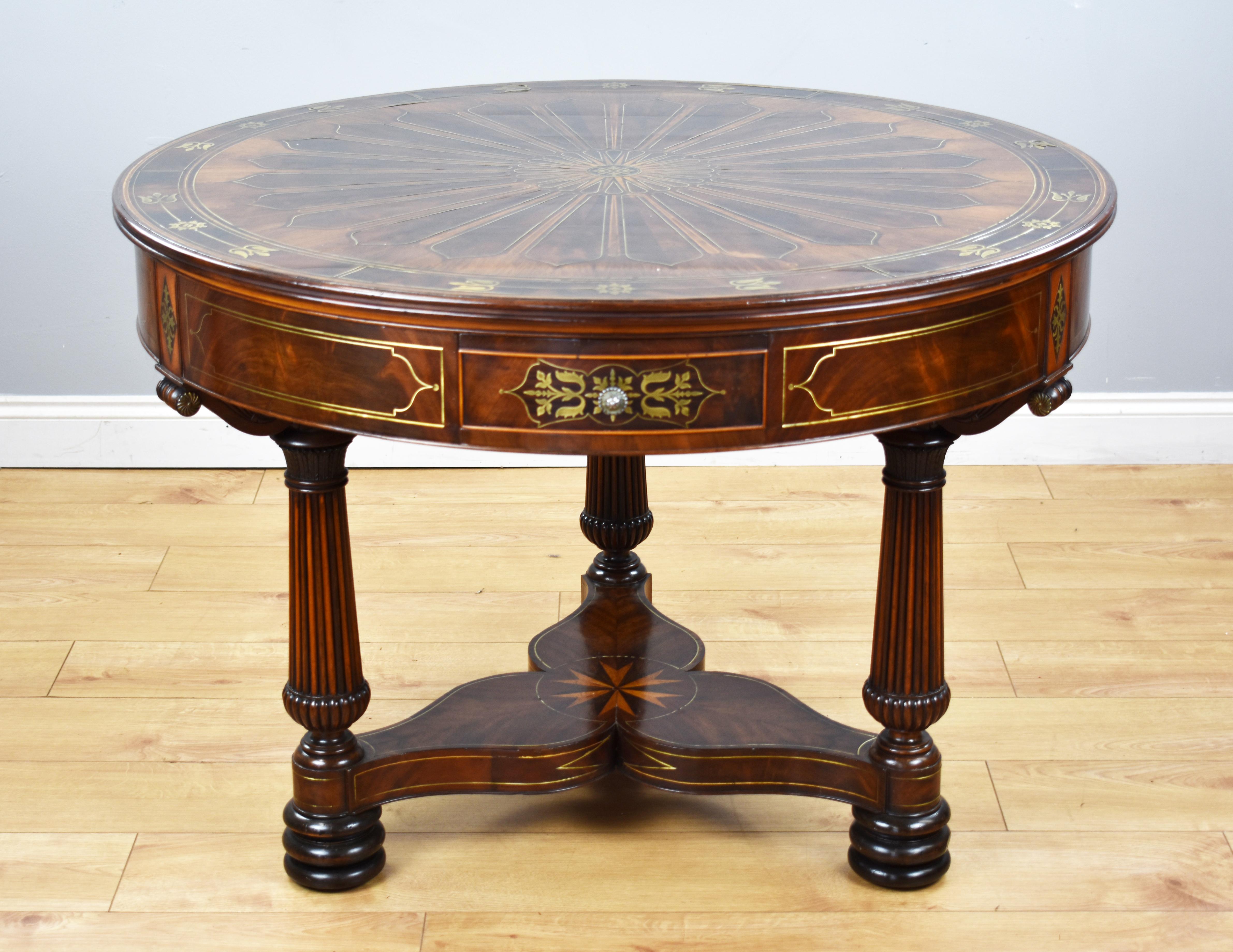 For sale is a fine quality Regency flame mahogany brass inlaid drum table in the manner of John McLean. Having a segmented top flame mahogany veneered and brass inlaid top, surrounding a central star, the paneled frieze fitted with three drawers