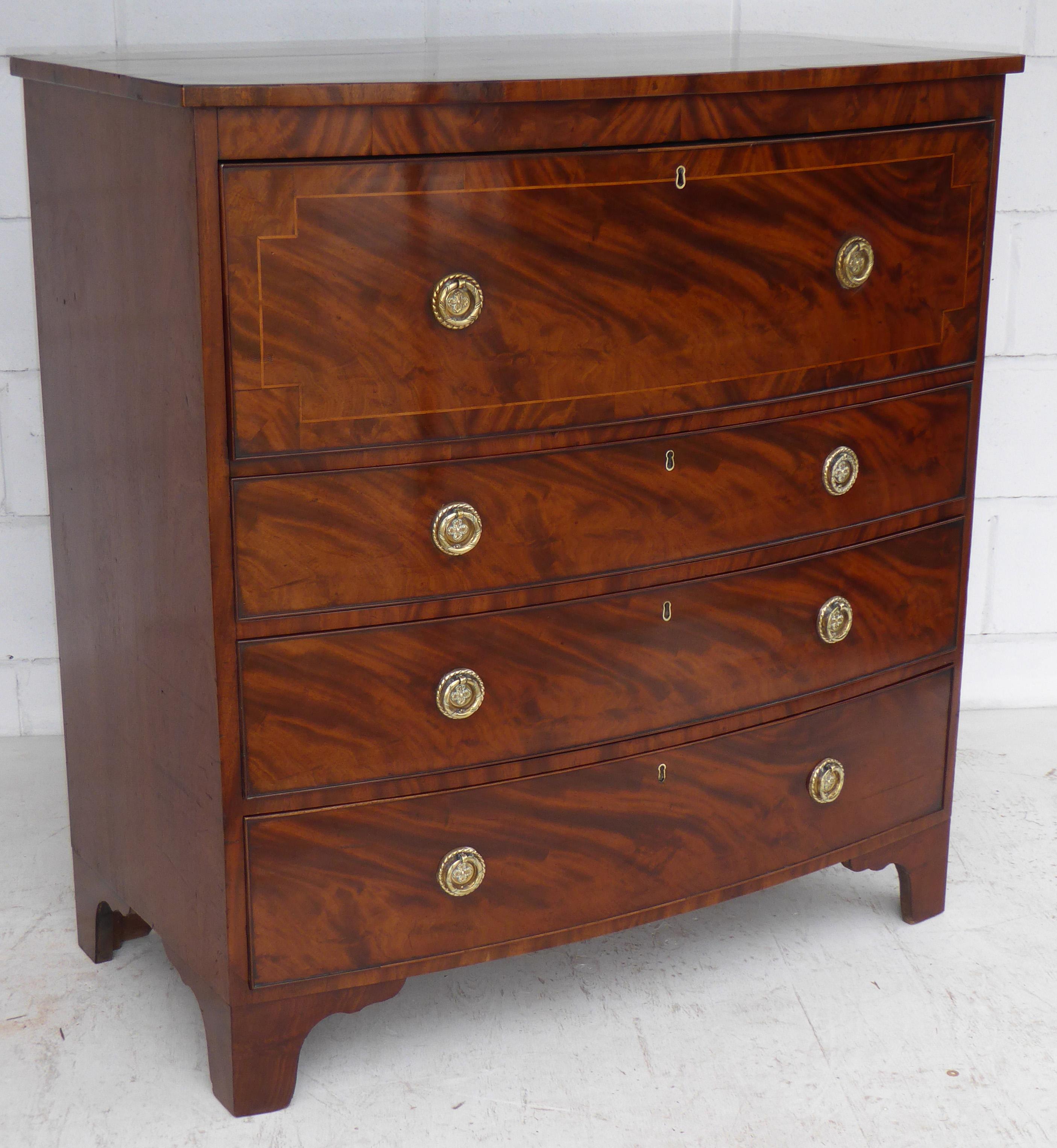 For sale is a fine quality Regency flame mahogany bow front secretaire chest. The top of the chest is nicely banded with flame mahogany and a satinwood line inlay. Below this is a large drawer at the top with a fall front opening to reveal a fully