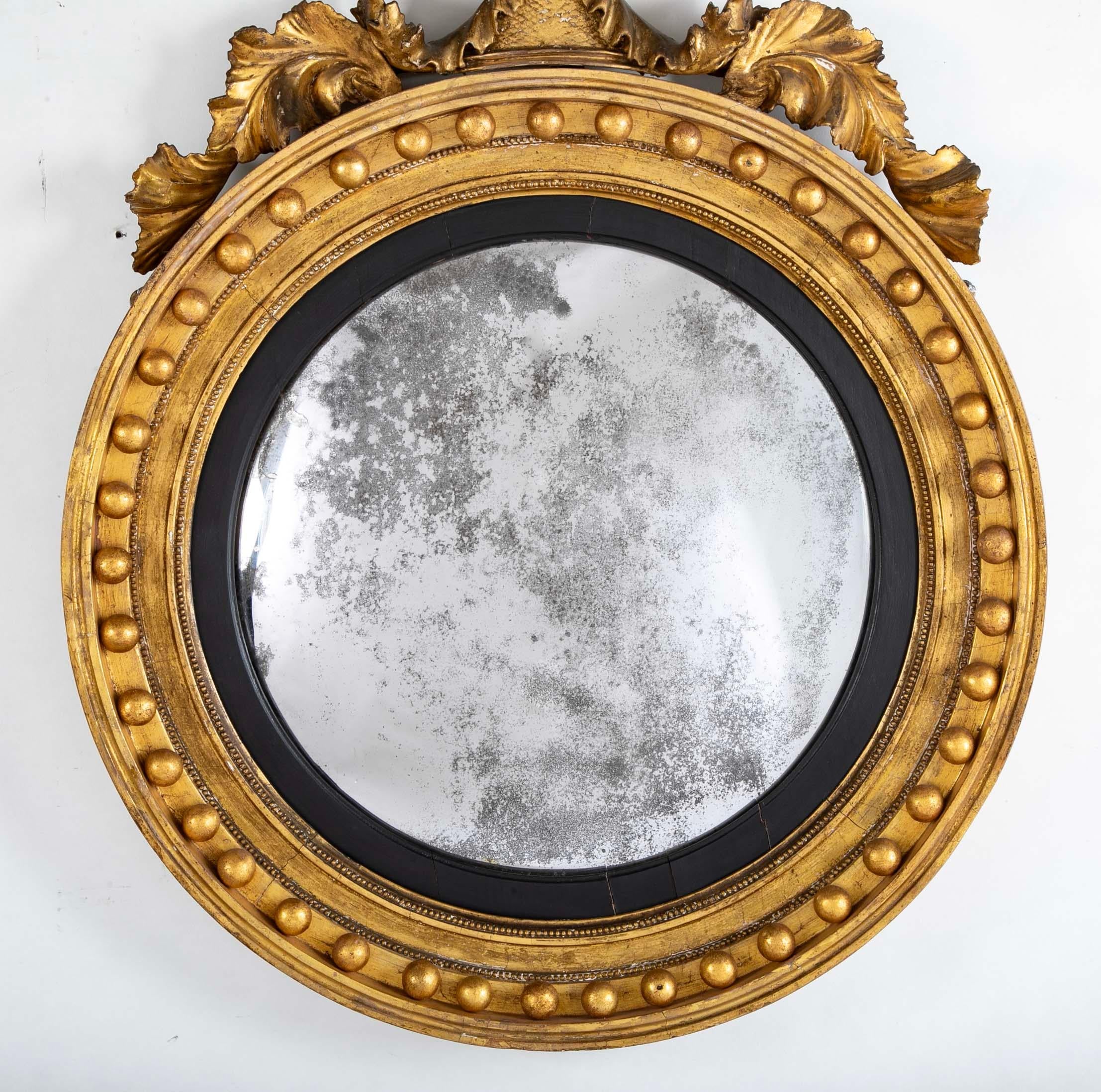 Regency Gilt Wood Convex Mirror, early 19th century.

The original mirror plate within a reeded ebonised inner molding, the round  frame mounted with spheres, crowned with a displayed eagle. A handsome mirror in the classic style of the Regency