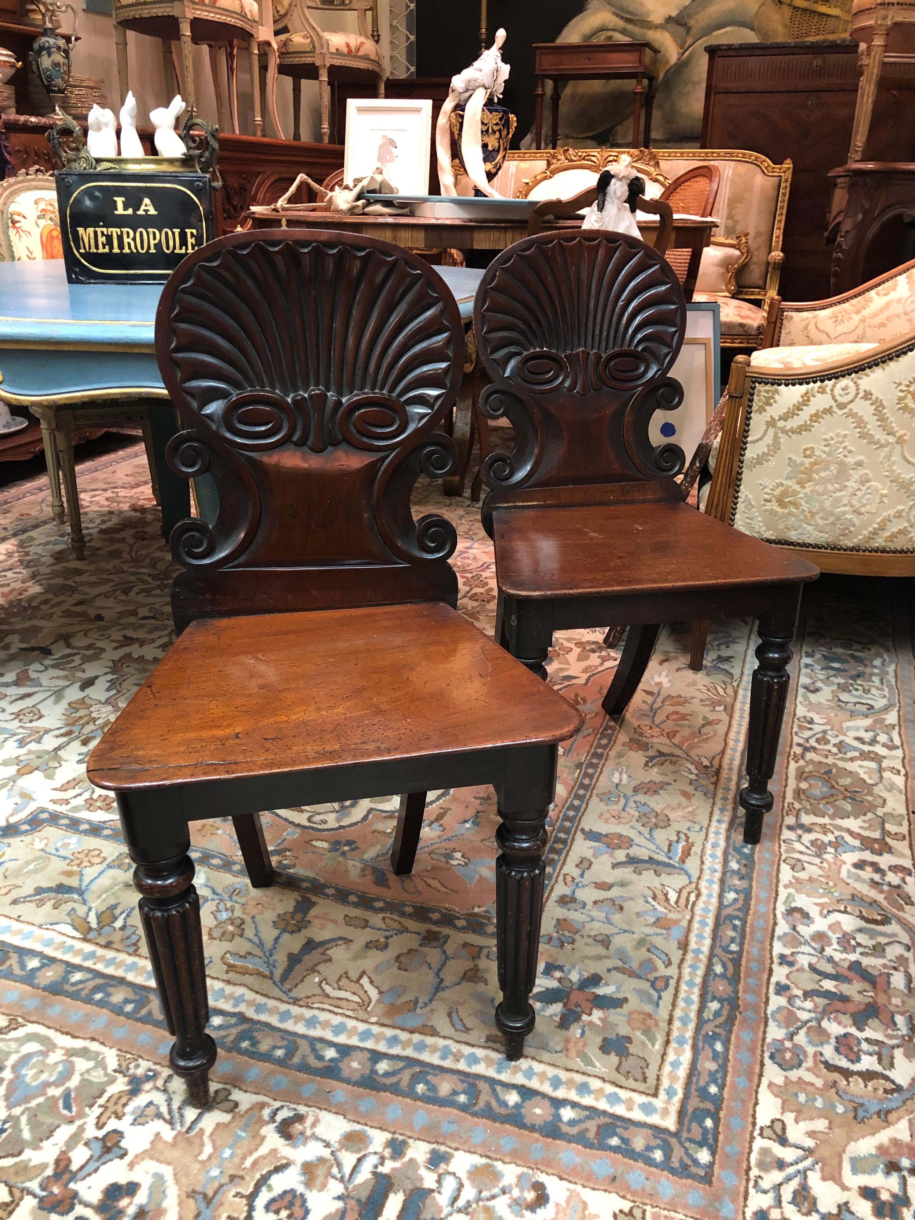 19th century English Regency mahogany hall chairs in the manner of Gillows, each with a scroll and shell carved back, on turned and ribbed front legs. Very good condition.
England, circa 1820.