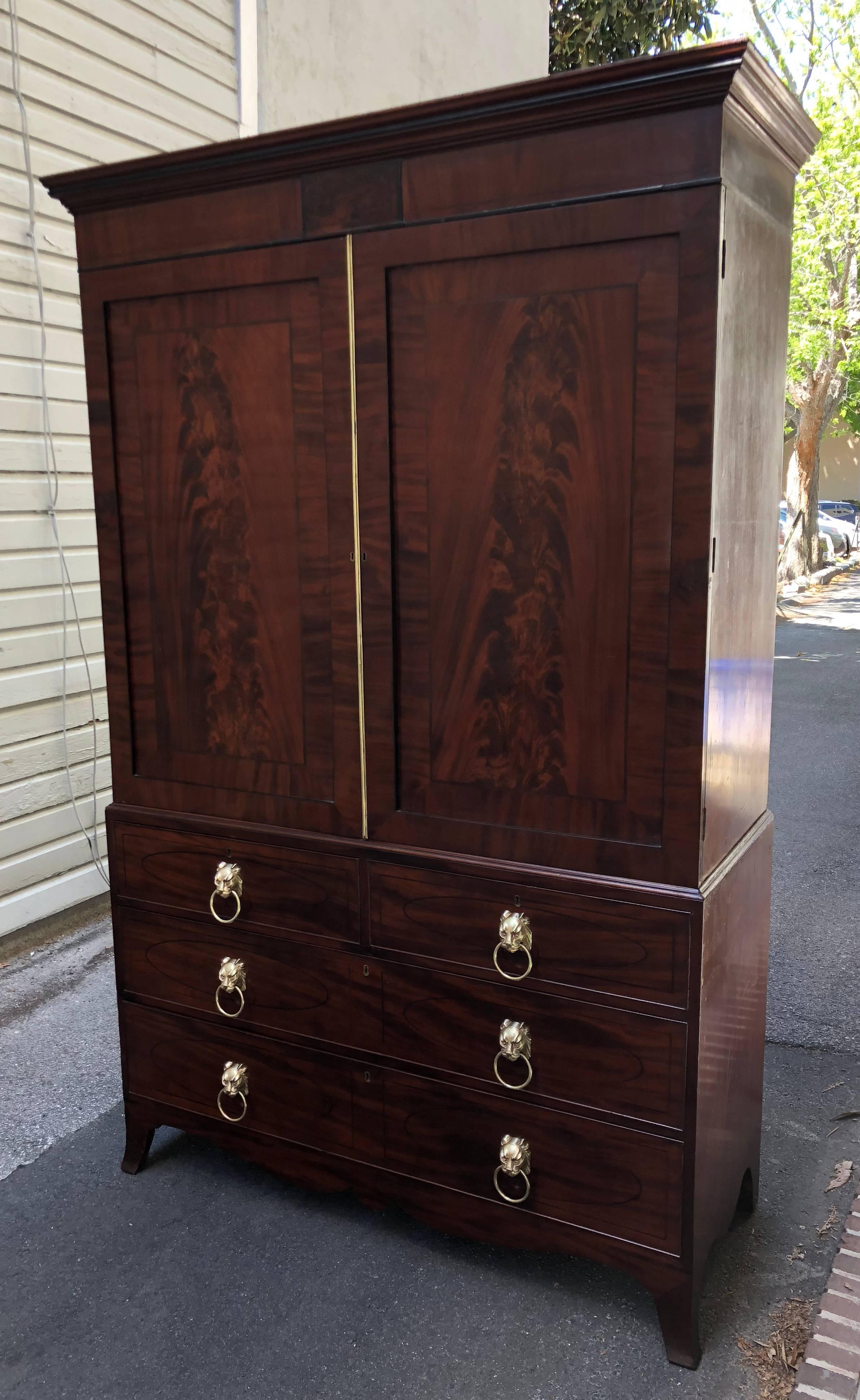 1810 English Regency linen press with original sliding linen trays at the top. Doors are bookmatched crotch mahogany with ebony inlay. The secondary wood is oak. Beautiful French foot and doré bronze leopard pulls, all original.