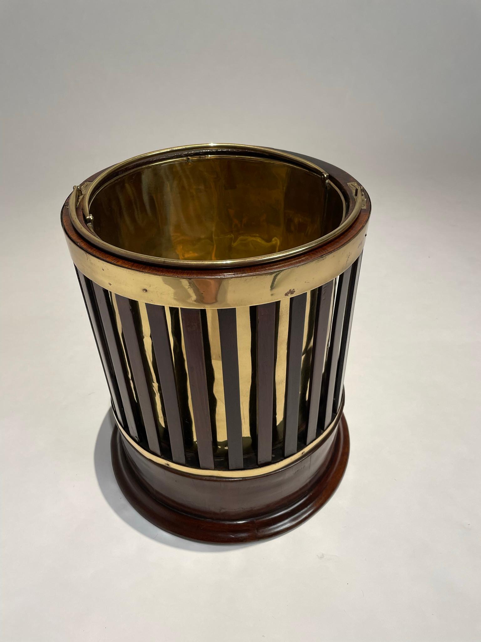 English Regency peat bucket of beautiful design, with slats of mahogany revealing the brass bucket liner within. I've never seen one like this. Retaining the original brass bucket liner.
This will make a very handsome waste bin, trash can or ice