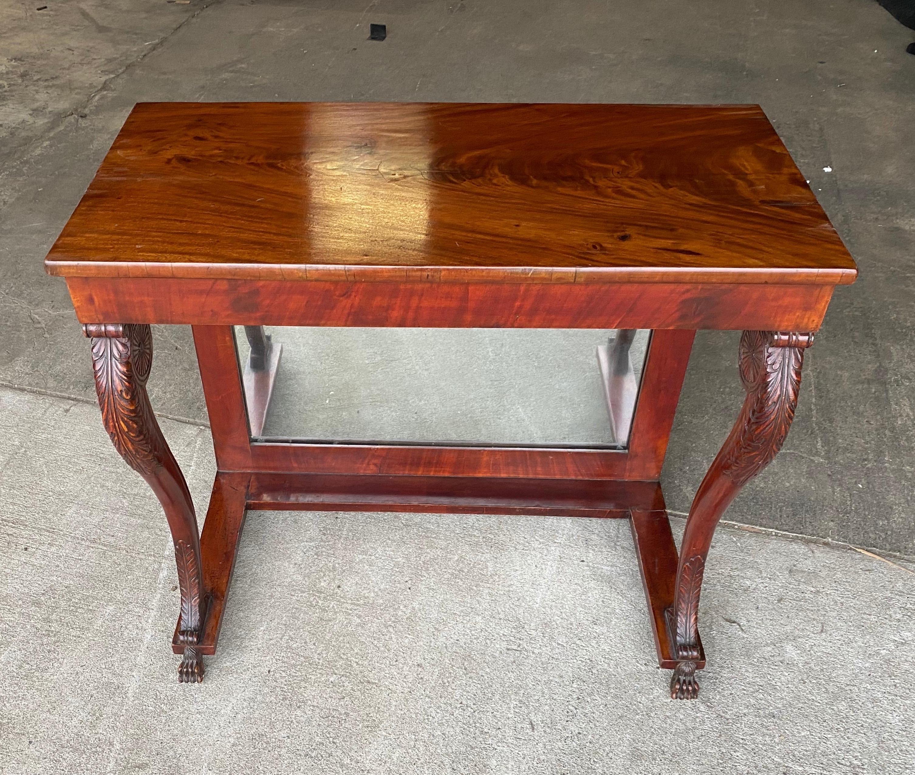 19th century English Regency mahogany console with paw feet and mirrored back. Highly figured mahogany top, carved knees and legs with acanthus leaves and terminating in paw feet.
