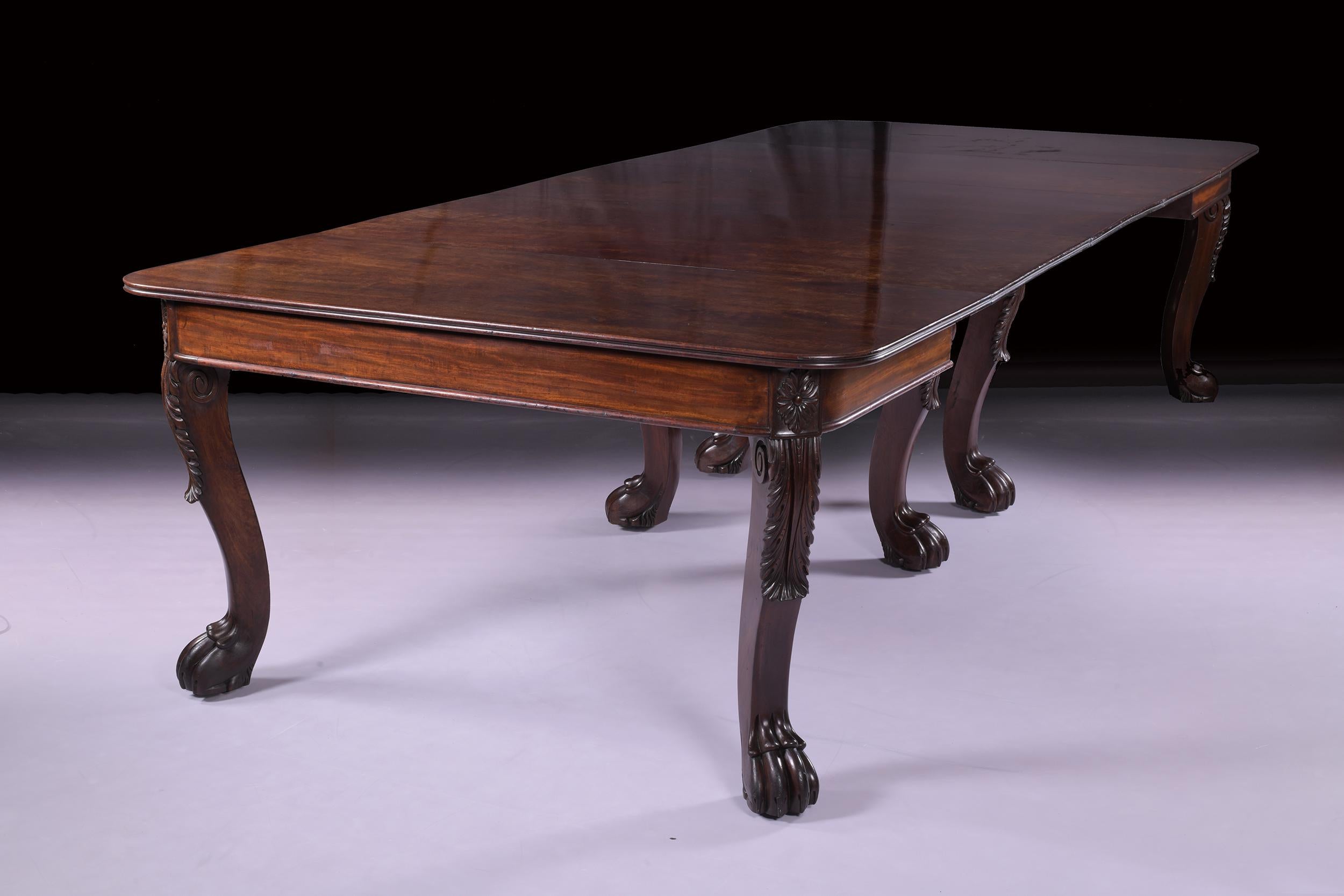 An exceptional 19th century English Regency mahogany dining room table, the rounded rectangular top with a reeded edge, raised on eight bold cabriole legs carved with acanthus-leaf spandrals terminating on hairy claw feet and hidden castors, with