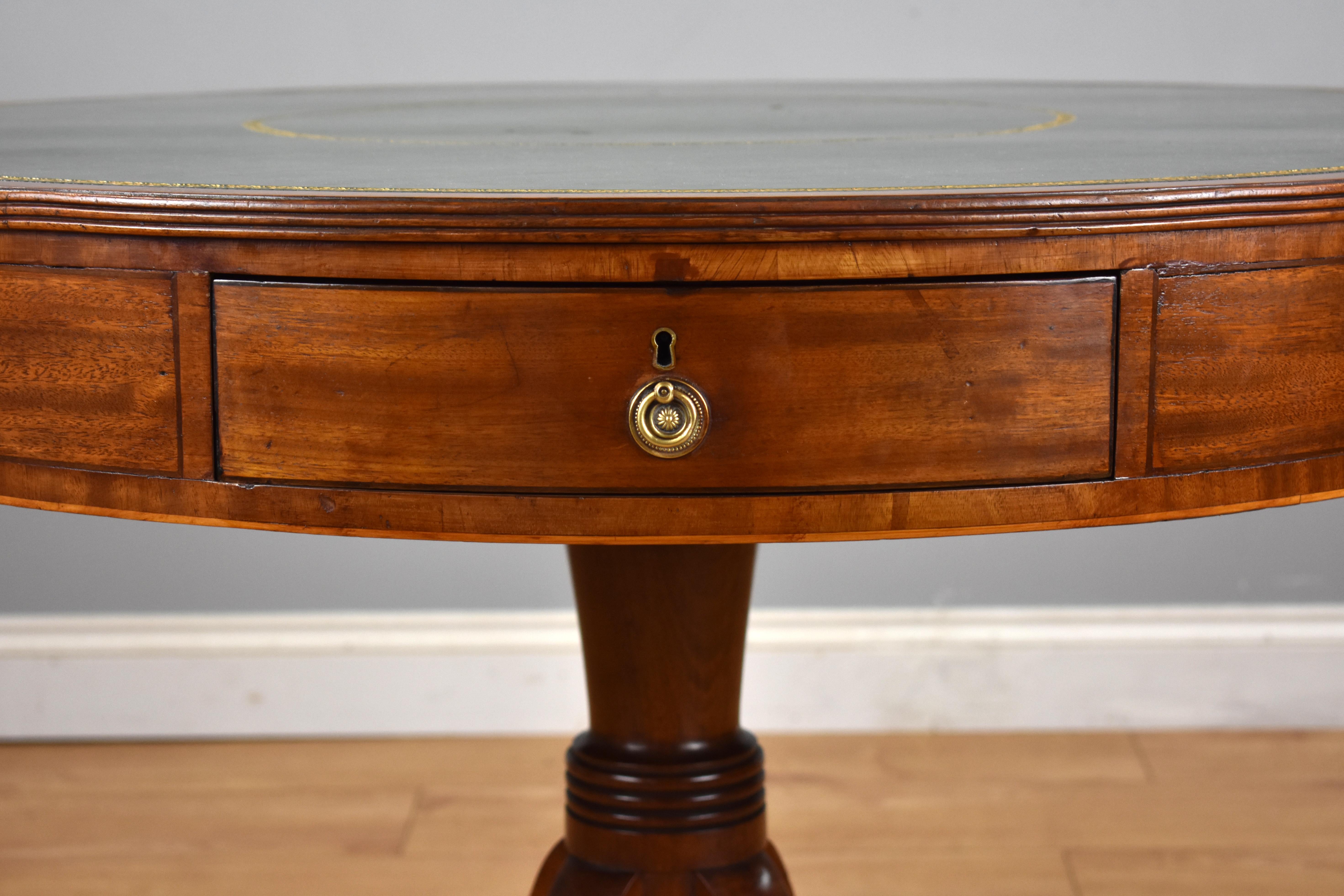 For sale is a very good quality Regency mahogany drum table, the top having a cross banded edge surrounded a green leather insert, decorated with gold tooling. Below this the frieze has four working drawers and four faux above a turned stem raised