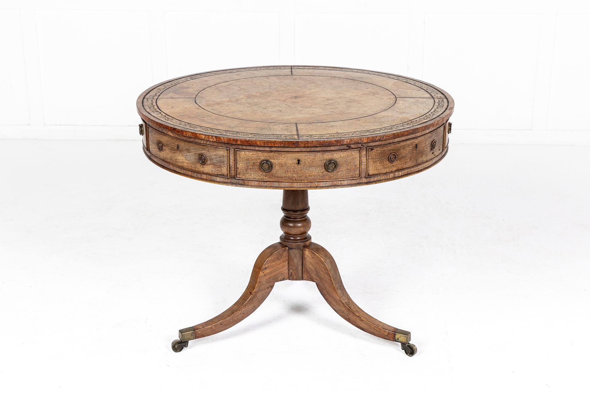 A 19th century English Regency mahogany, revolving drum table having a beautiful, original tooled leather segmented top with a burr yew cross banded edge. Having an arrangement of four oak lined drawers and four false ones, with brass handles.