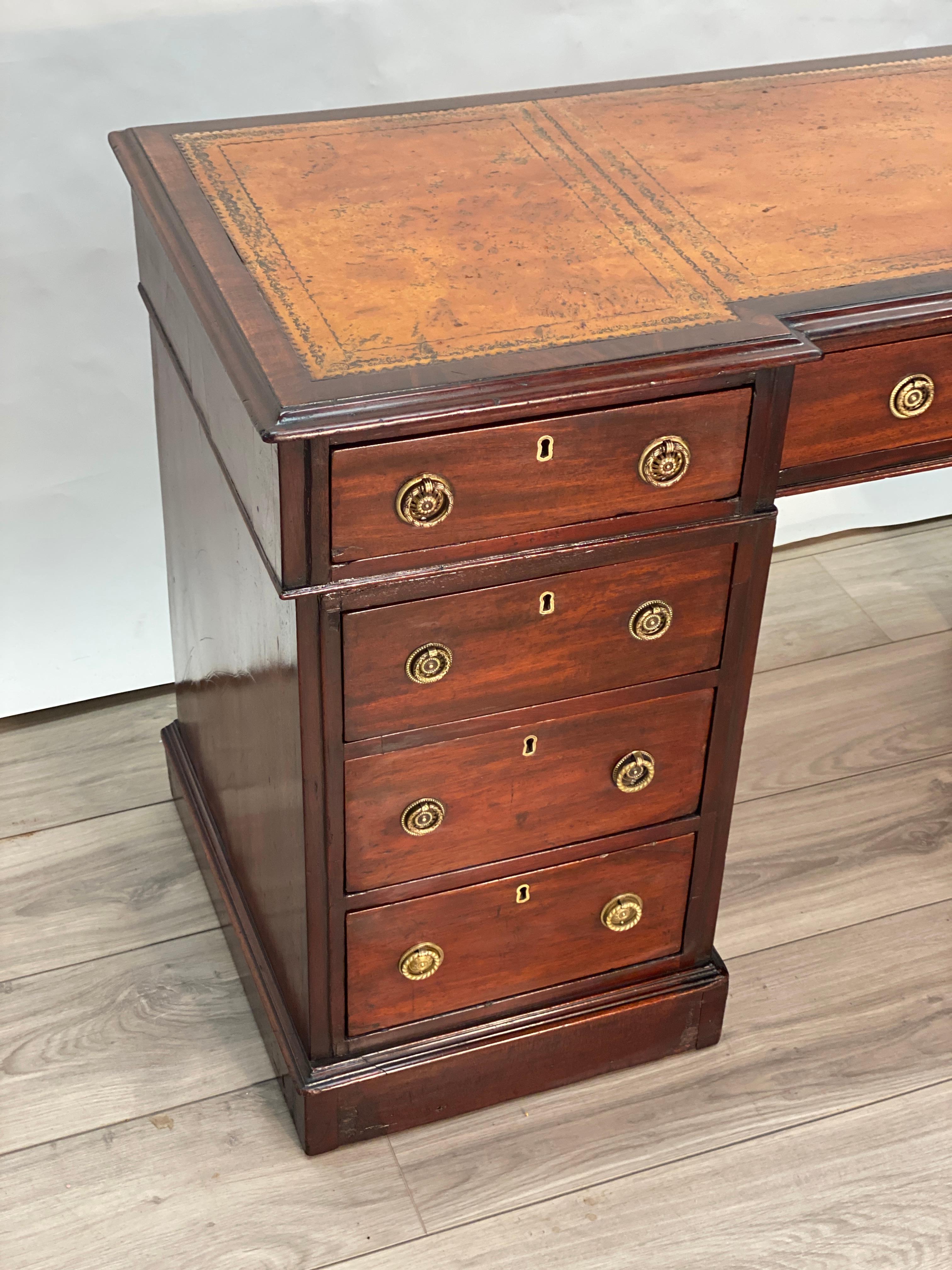 This is a handsome mid 19th century English knee hole pedestal desk. There are three sections to the desk. The side cabinets are mahogany and pine woods, each fitted with three graduated drawers and brass ring pulls. The top section is fitted with
