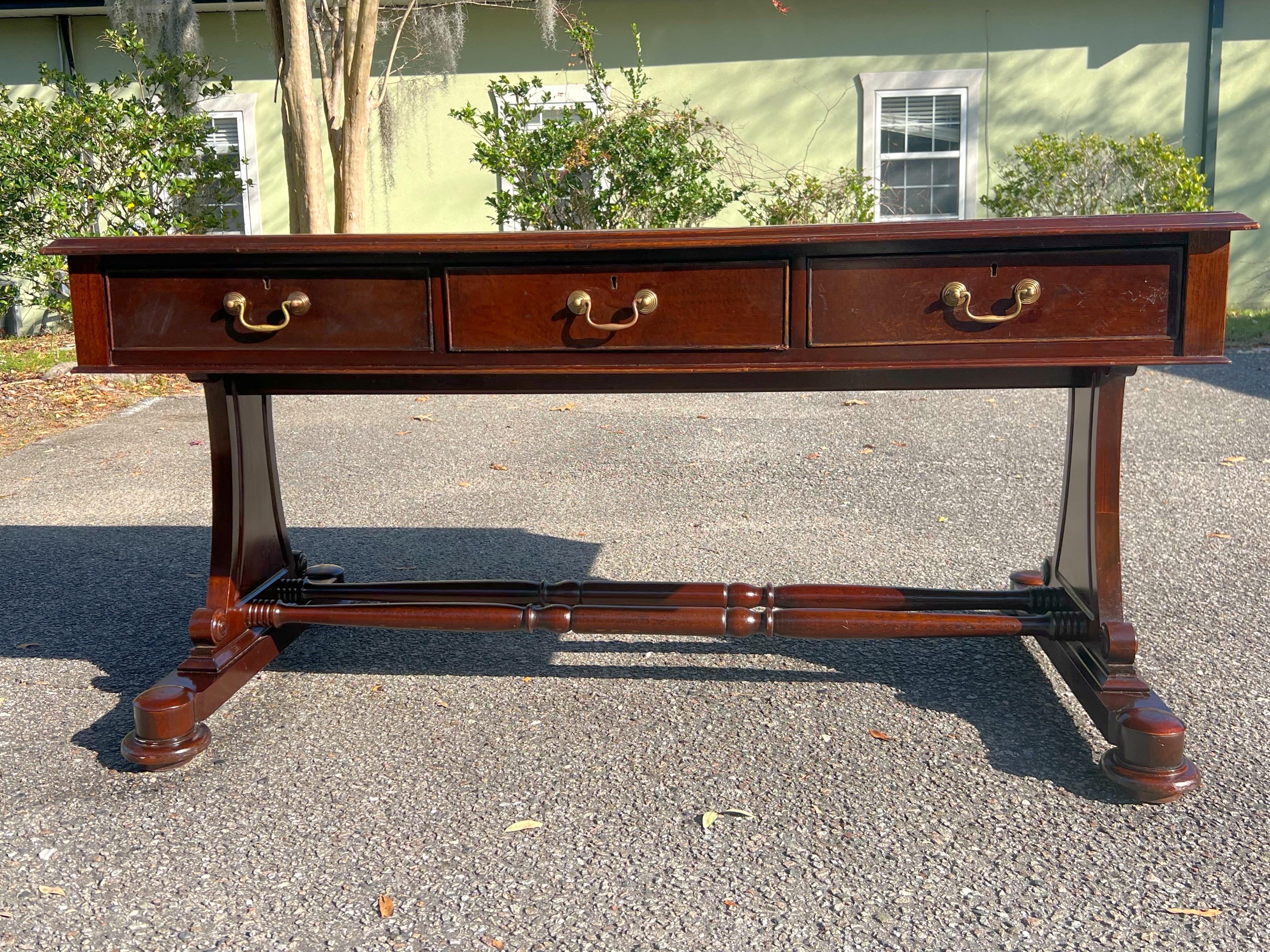 19th Century English Regency Mahogany Leather Top Writing Desk. Gold embossed floral around the leather. Satinwood trim surrounds the solid mahogany desk.  A beautiful turned double stretcher connects the legs.  3 of the drawers are deep and