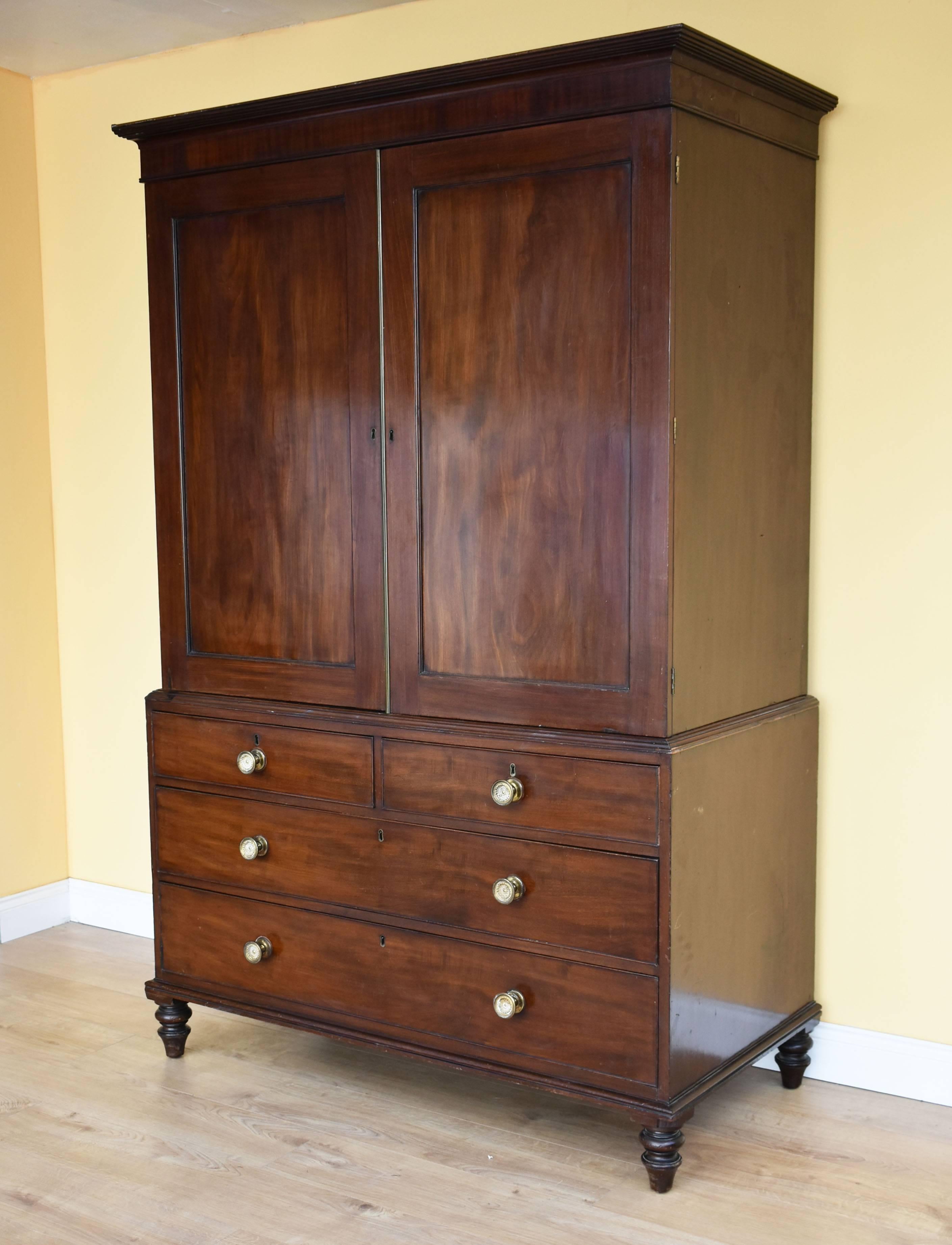 For sale is a good quality Regency mahogany linen press, with a stepped cornice over two paneled doors, opening to reveal ample hanging space. Below this, there is an assortment of four drawers, two short over two long. The press stands on elegantly