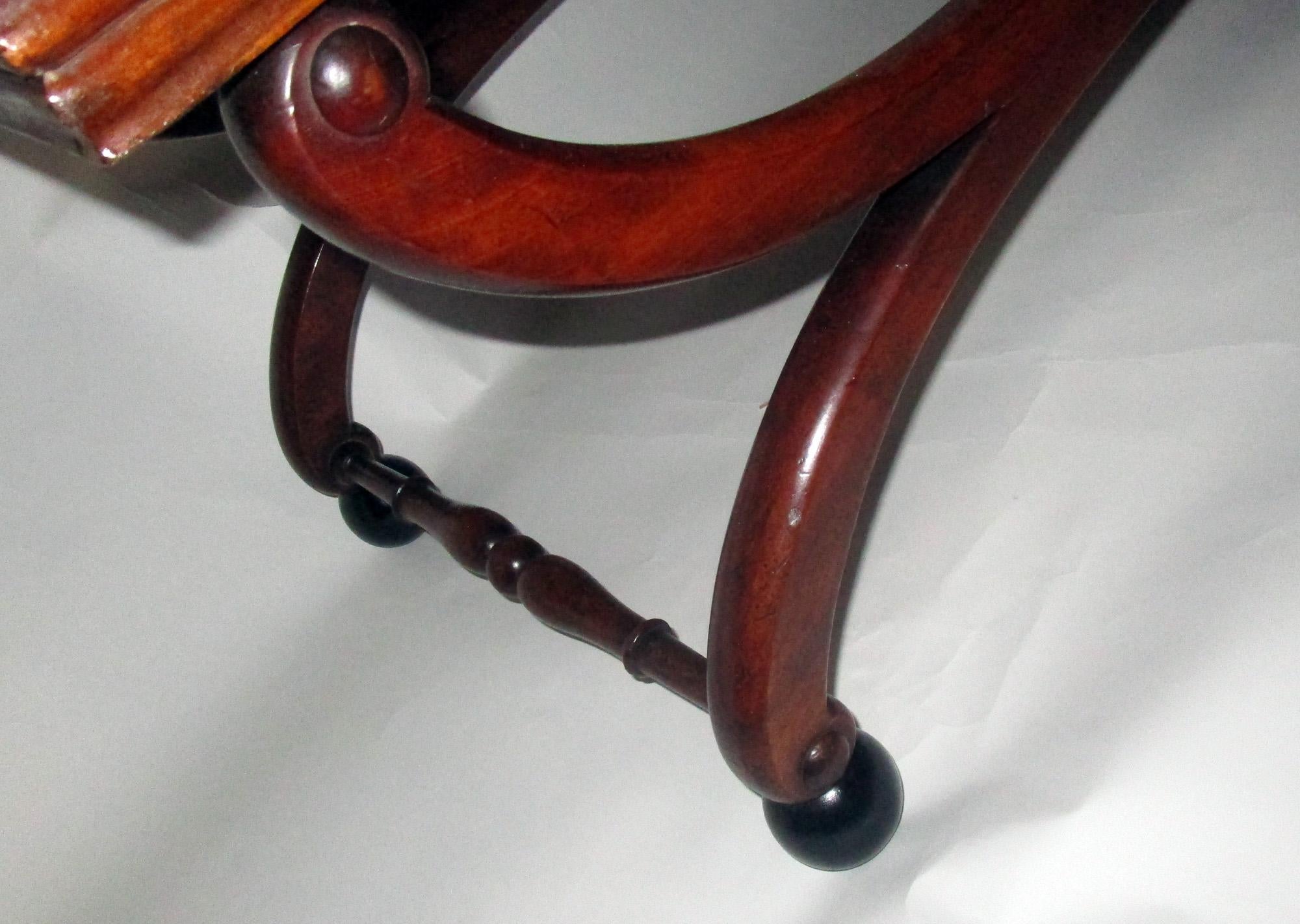 19th century English Regency period mahogany bench in graceful scroll form. Upholstered lift out seat. A very versatile piece suitable at the end of a bed, in front or in back of a sofa, in a hallway or used as a fireplace bench. Sturdy