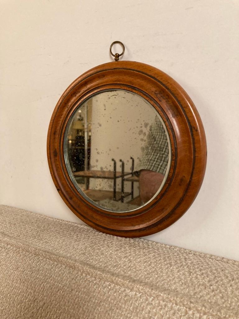A sweet little early 19th century round mirror carved from a single piece of fruit wood and retaining the original glass. Only 7.4 inches diameter, this makes a charming accent or addition to your wall of mirrors. Warm honey patina.