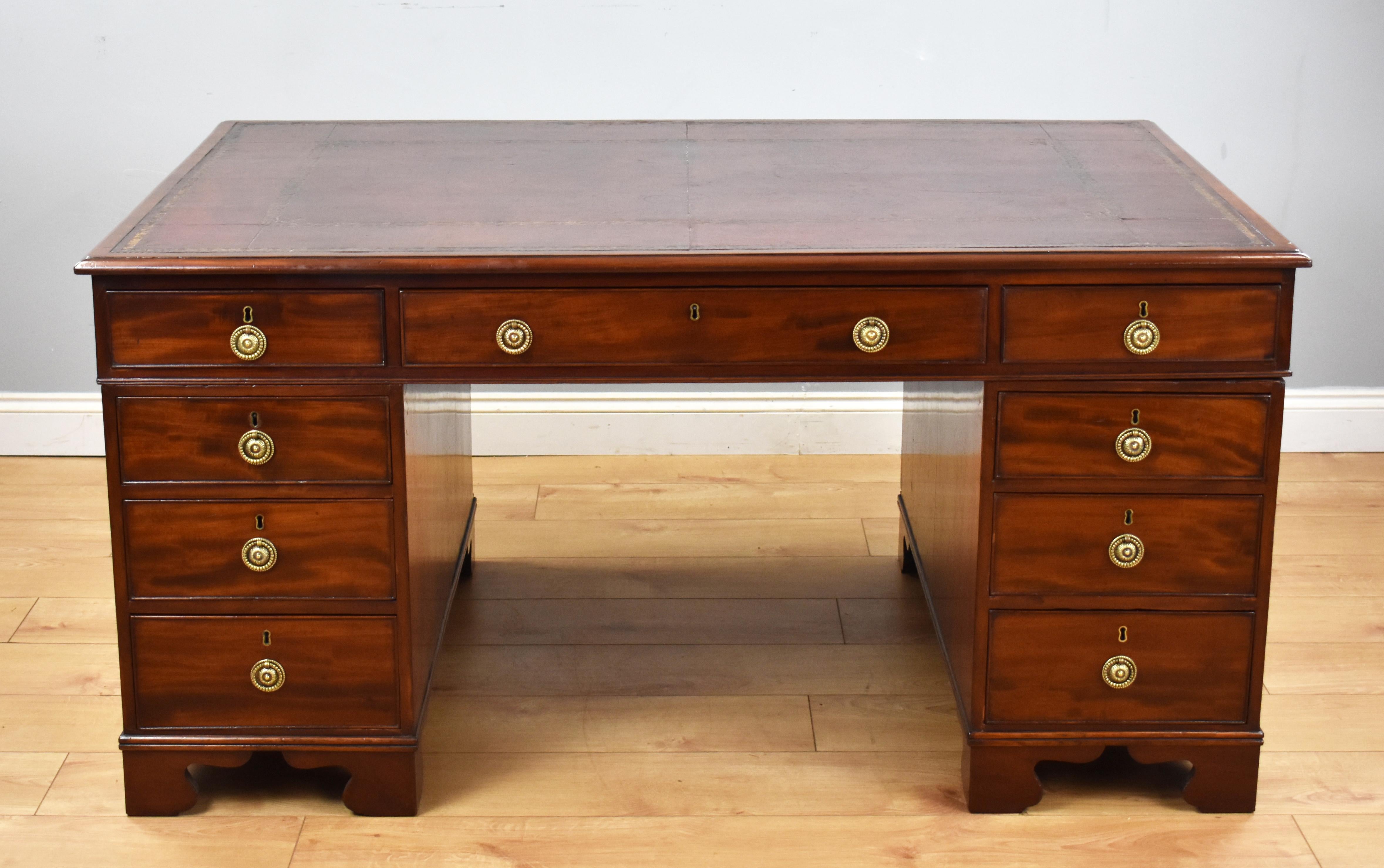 A good quality Regency mahogany partners desk, having a dark red leather insert, decorated with gold tooling above three drawers in the top, with a further three drawers on the opposing side. The top fits onto two pedestals, each having graduated