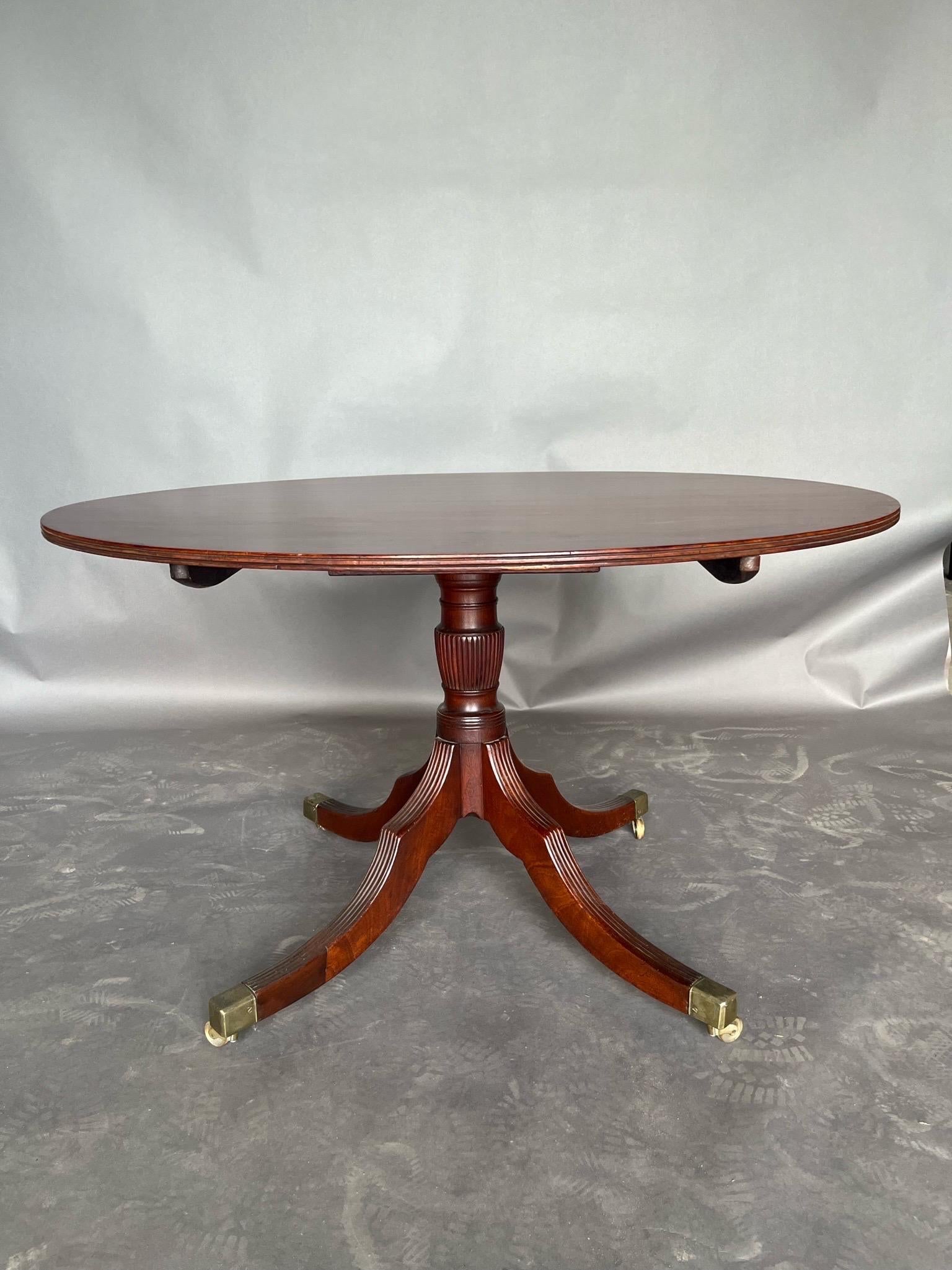 19th century English Regency period oval mahogany breakfast table or center table. Fabulous color and grain top, nice reeded legs and original castors. 