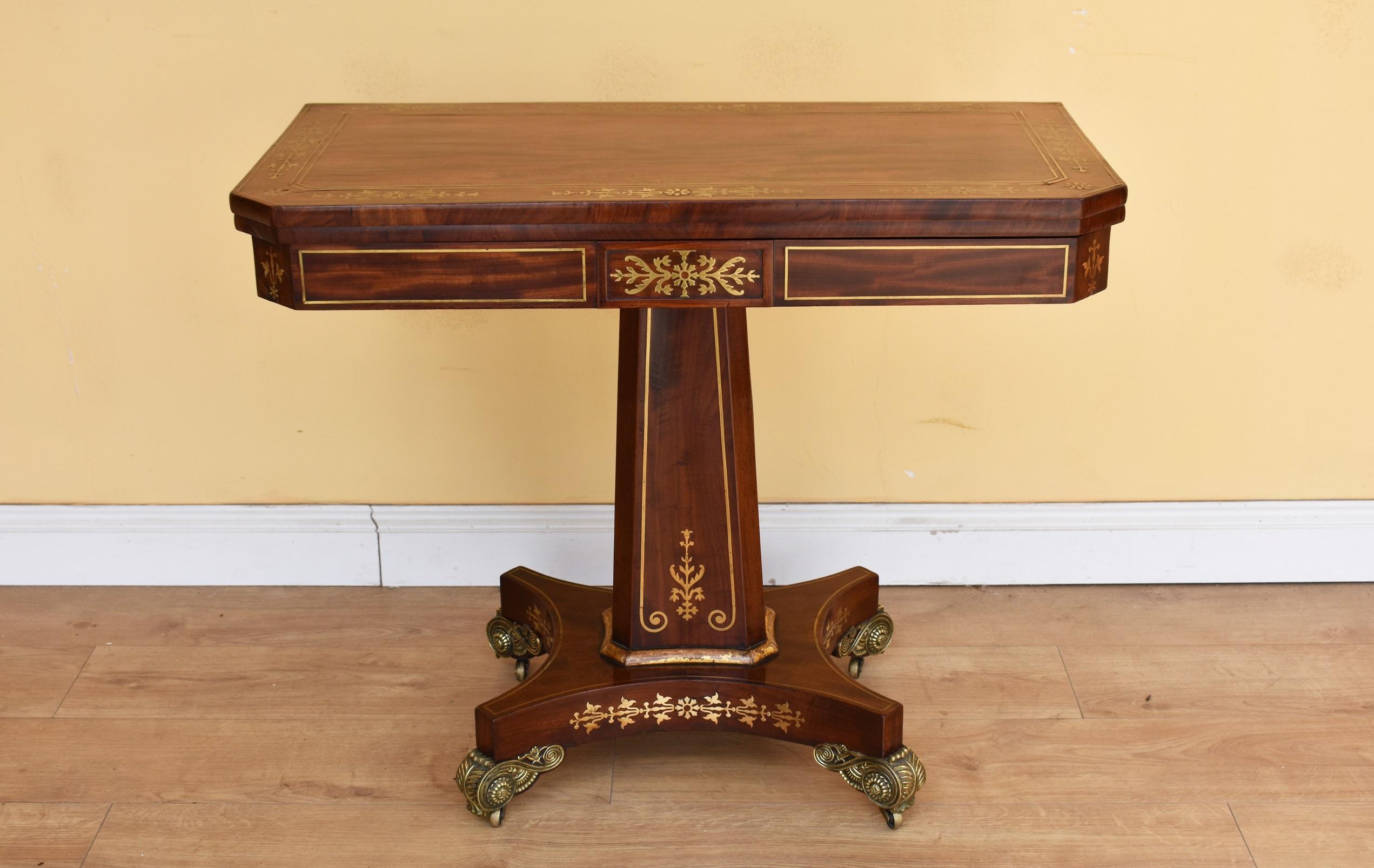For sale is a good quality Regency rosewood and brass inlaid card table. The top is nicely inlaid and swivels to reveal storage space for cards etc. This then folds over to show a green baise above a flared column. The piece is raised on ornate