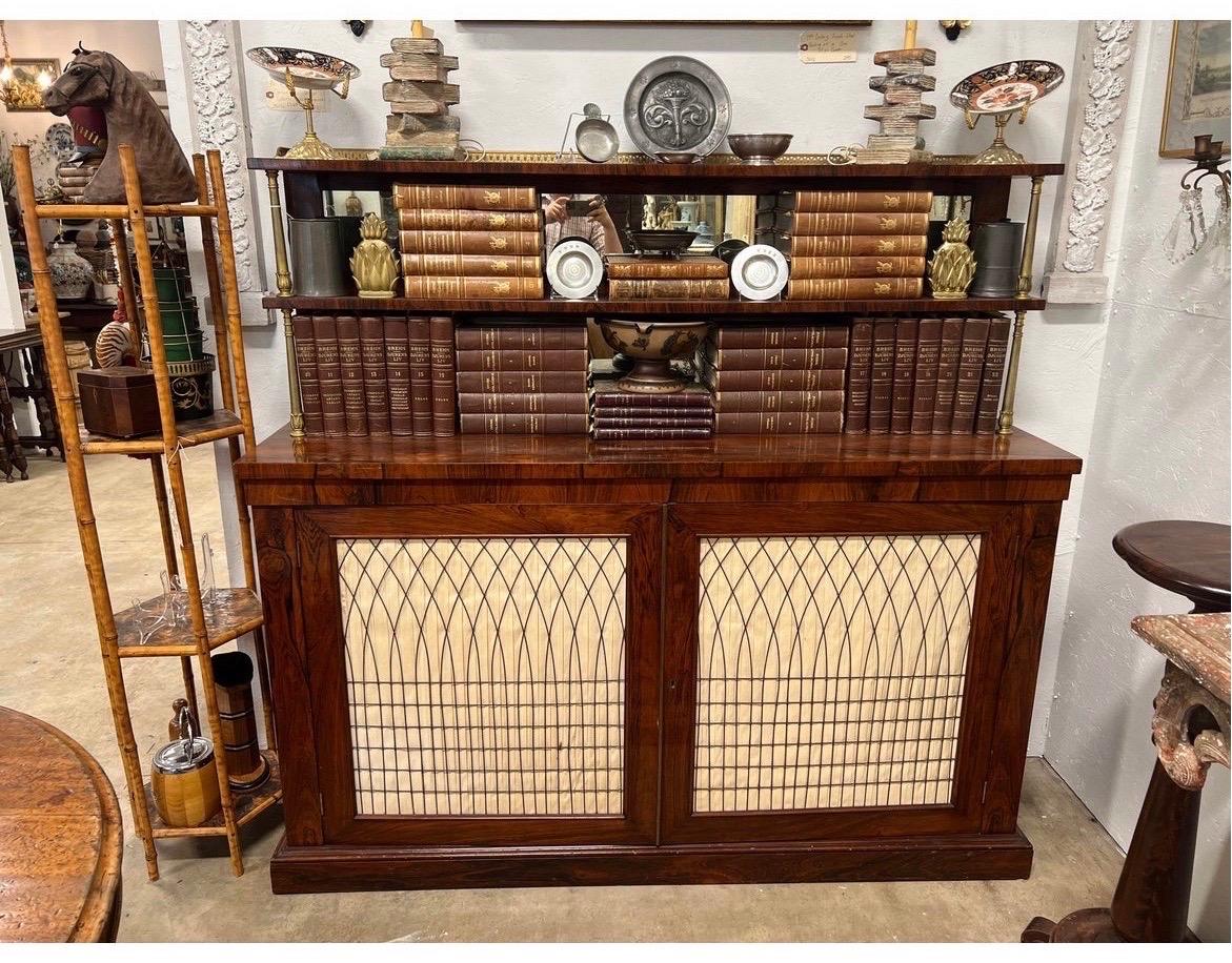 A spectacular english regency period sideboard / server with three tiered back support (which detaches from bottom). Executed in fine rosewood detailing, brass rail trim to top, chicken wire caged door (linen can be removed). Distressed mirror