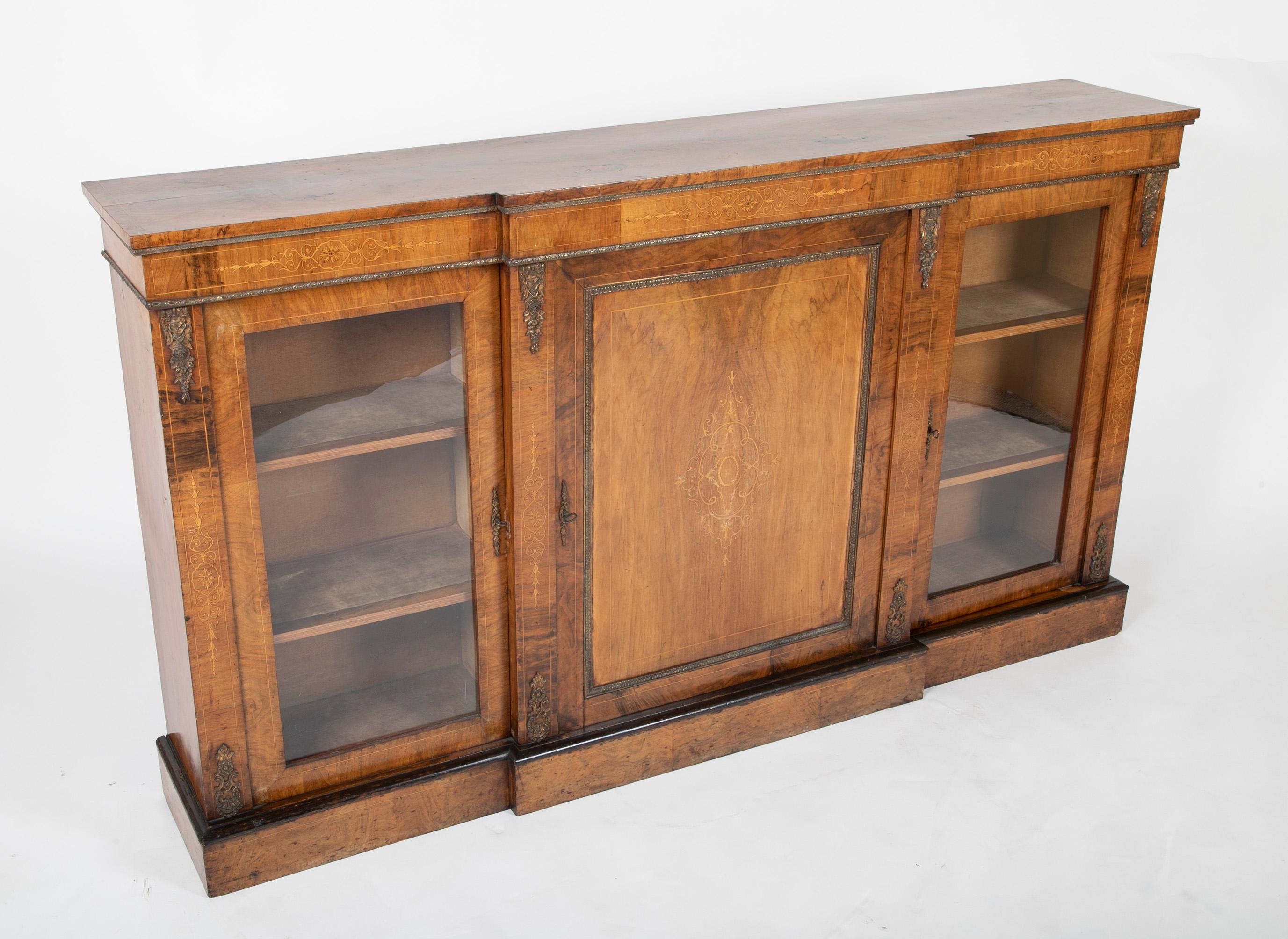 Handsome 19th century English credenza with beautiful figured rosewood veneer and fruit wood inlaid designs. With bronze moldings and mounts. Two glass fronted doors flank a large central door with delicate inlaid decoration. This piece has a very