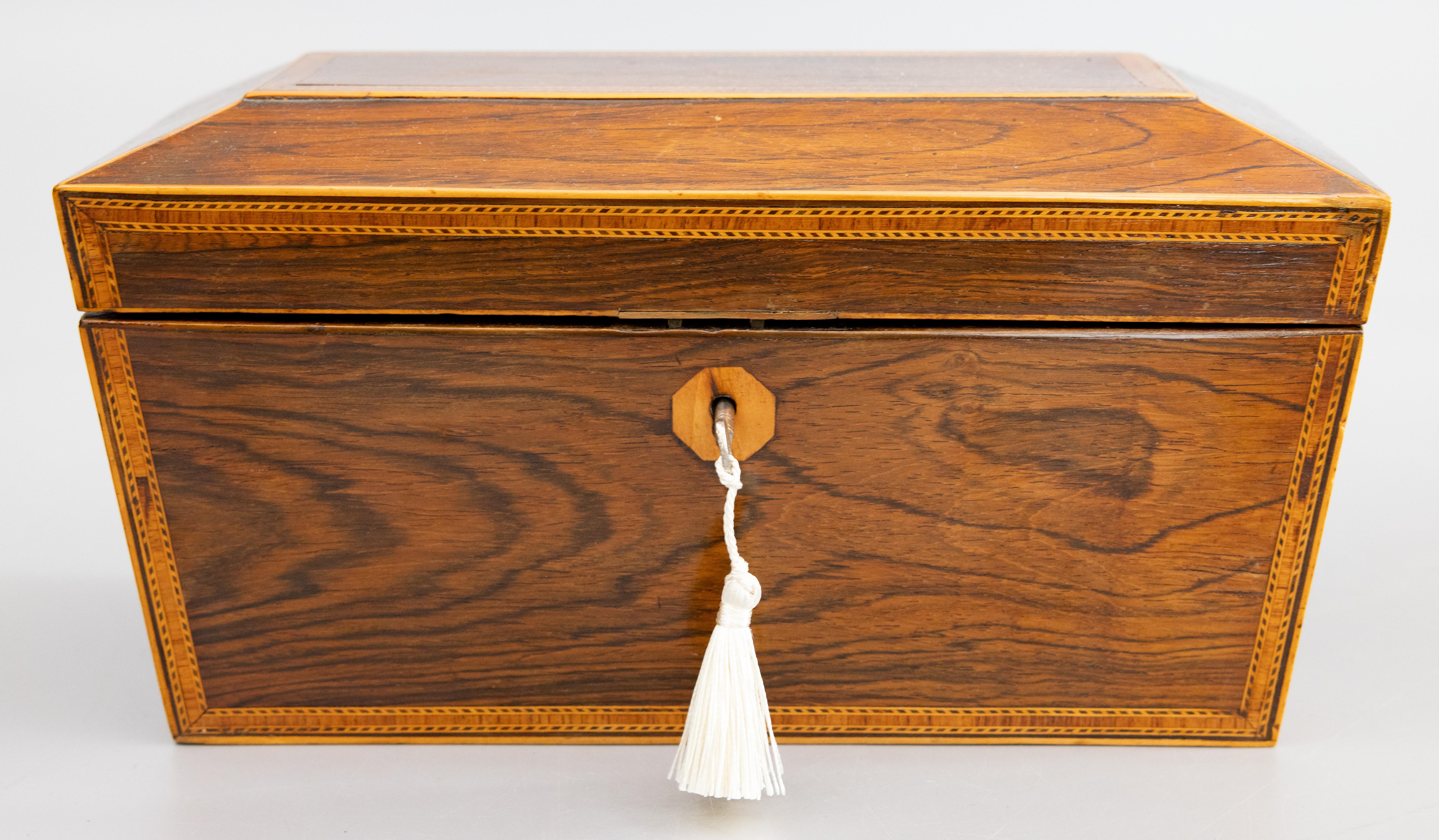 A superb antique English Regency style rosewood sarcophagus casket box with lock and key, circa 1850. This fine antique box has a lovely sarcophagus form accented with contrasting inlaid bands and ormolu lion ring handles. This large hand crafted