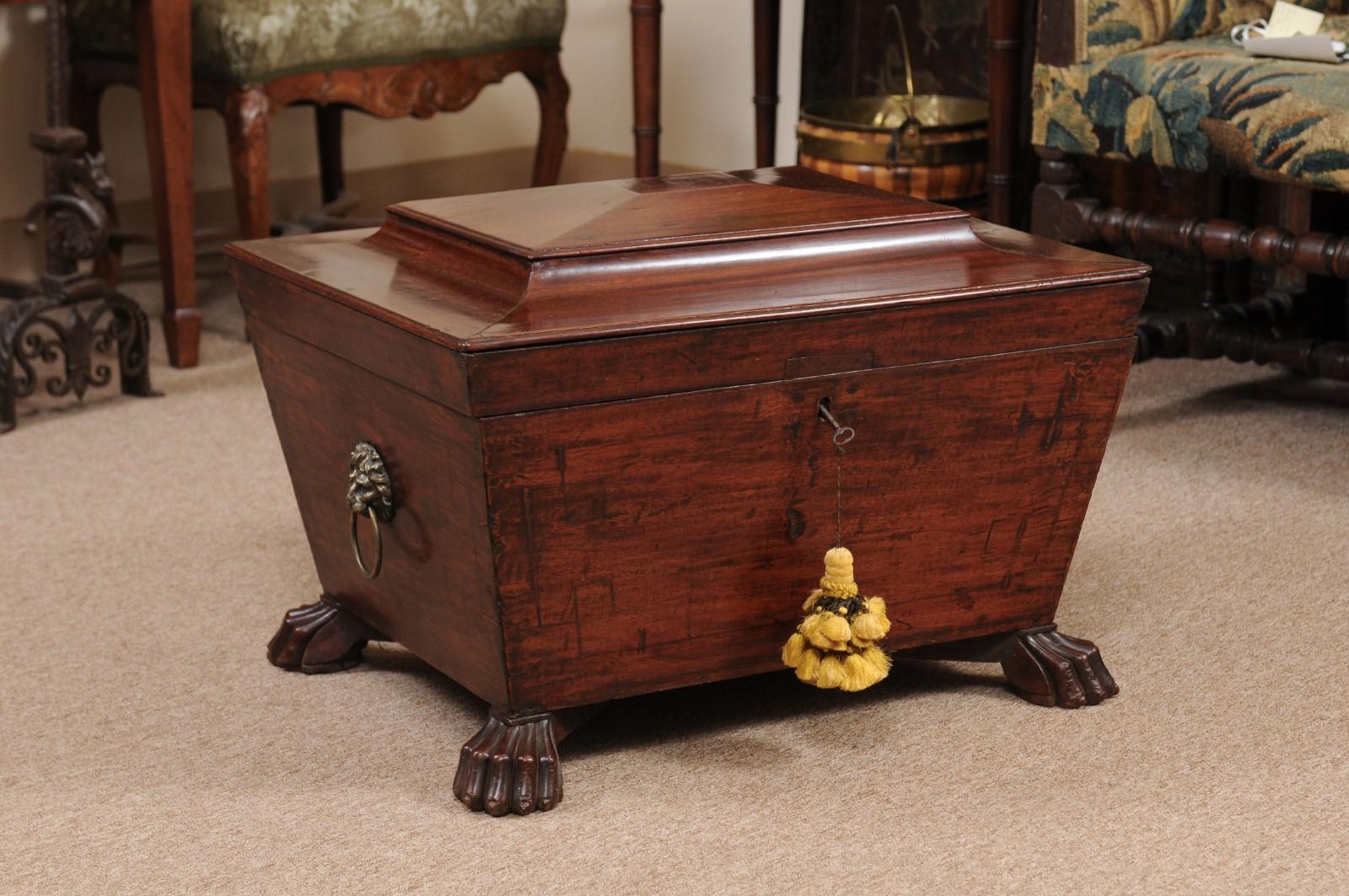 Regency mahogany cellarette with sarcophagus-form, paw feet, and lion's head handles, 19th Century, England.