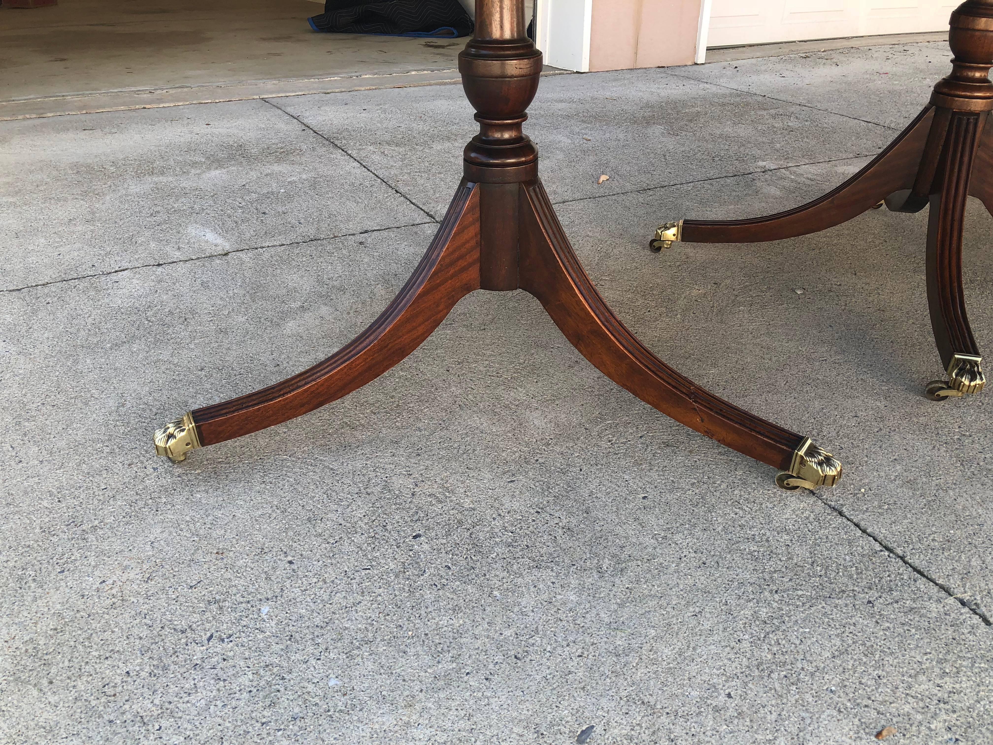 19th century English Regency solid mahogany three-piece banquet table. One leaf is slightly darker due to storage. The middle pedestal has four legs and the two banquet ends has three legs with bronze casters.
 