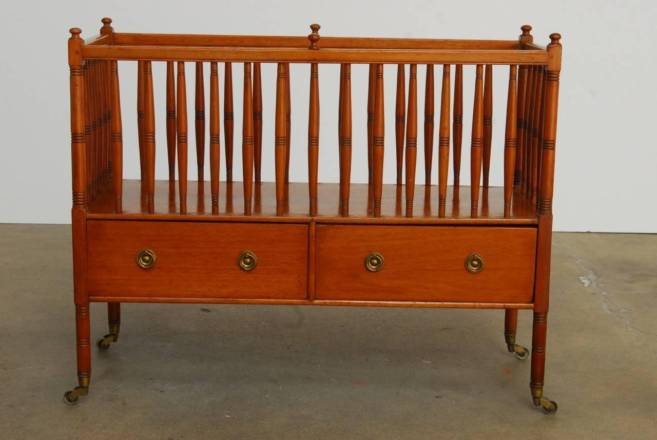 Large 19th century English regency style Canterbury constructed from mahogany. Fronted by two large drawers measuring 4.5 inches deep. The rack is enclosed with turned spindles and supported by turned legs ending in brass casters. Decorative finials