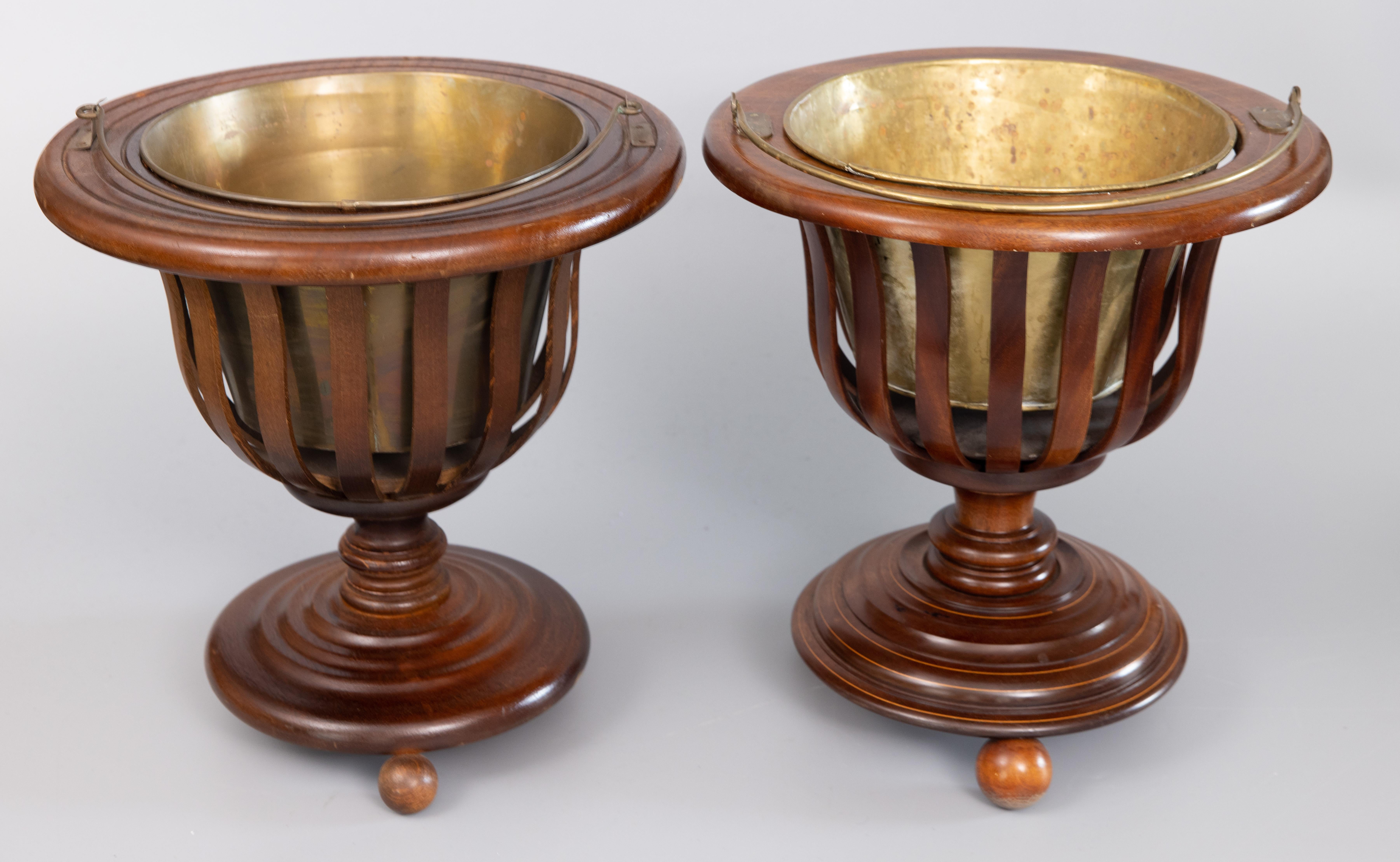 A superb set of two 19th Century English Regency style slatted mahogany peat buckets / jardinieres / planters with the original removable brass liners. These stately jardinieres are a near pair with slight differences, both finely carved with ball