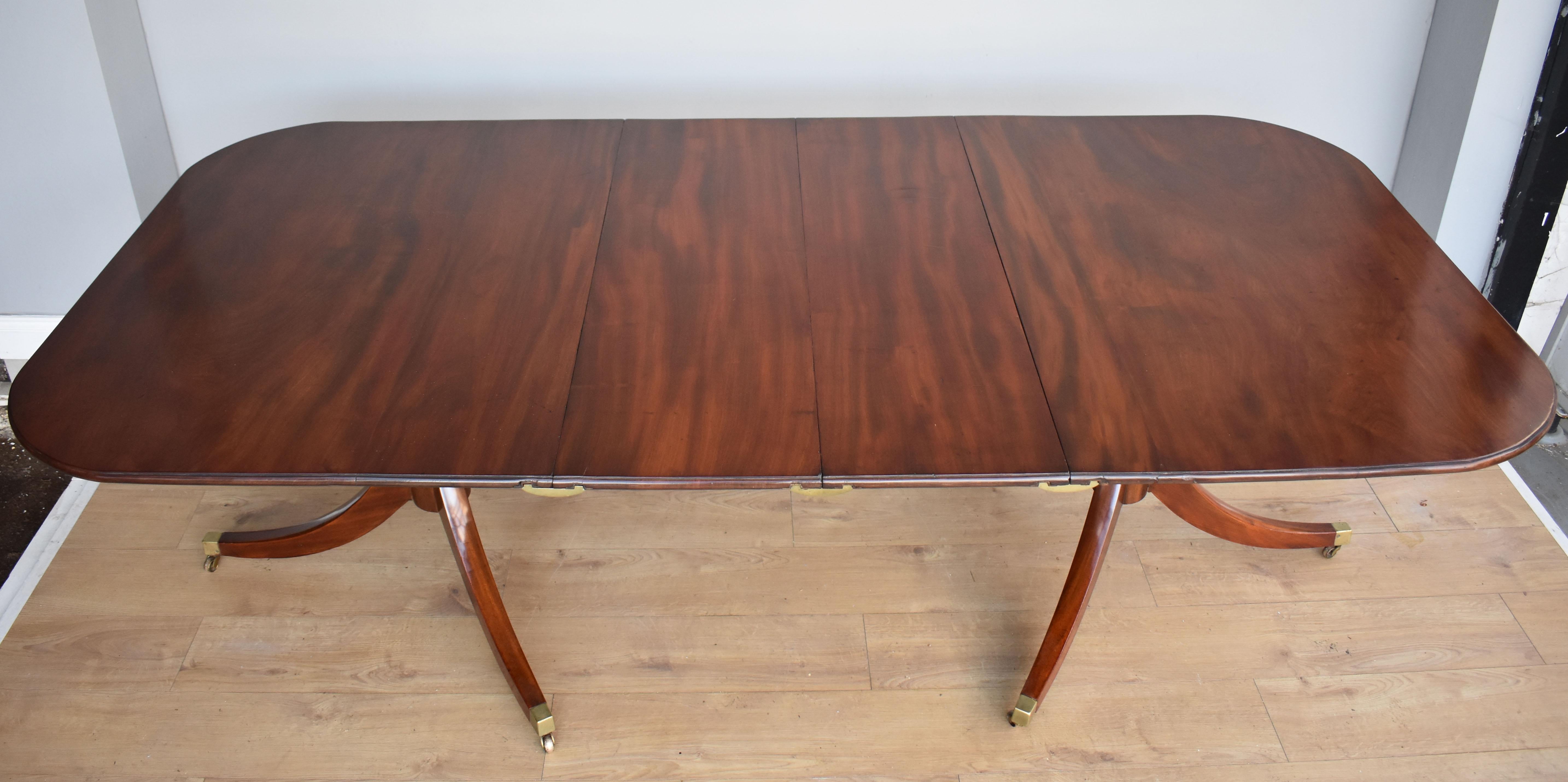 For sale is a good quality Regency style mahogany pedestal dining table. The tops being made from beautifully figured solid mahogany, the table comes complete with two additional leaves. Standing on a turned base with three splayed legs terminating