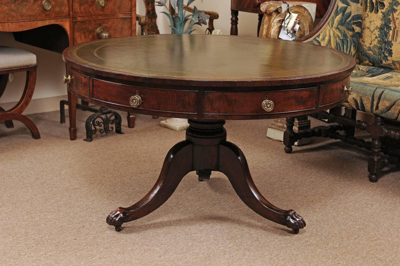Rotating mahogany rent / library table with pedestal base featuring paw feet and embossed green leather top, dates from 19th century, England.