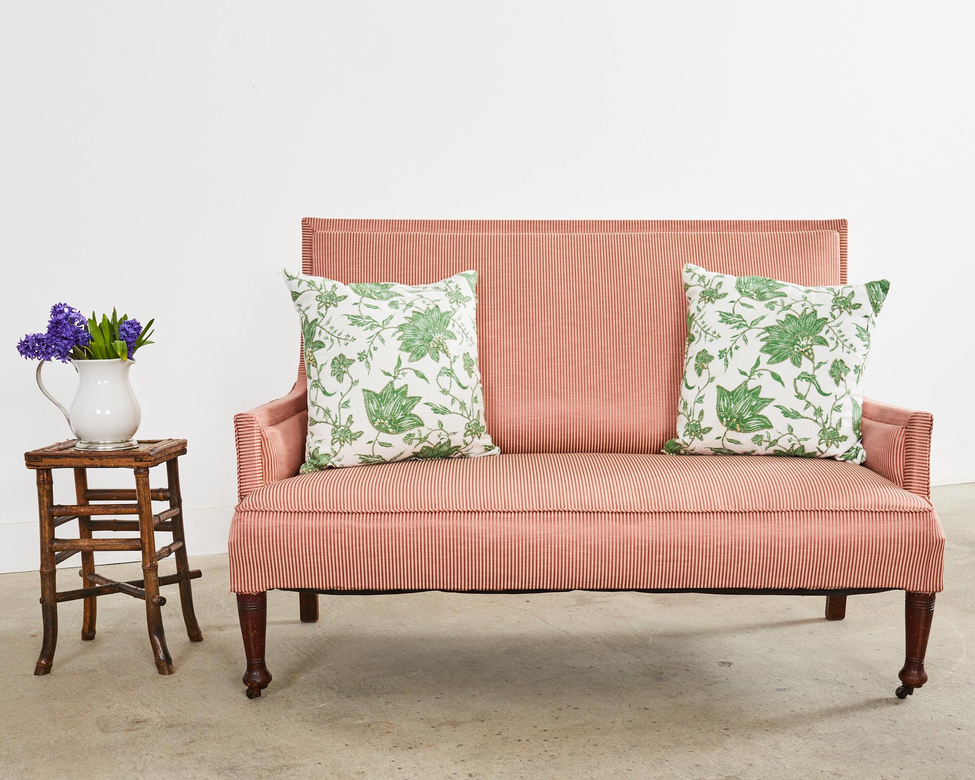 Canapé ou sofa rembourré en acajou de la fin du 19e siècle, de style régence anglaise. Magnifiquement réalisée avec une restauration ancienne, elle présente un haut dossier carré en acajou qui s'incurve gracieusement jusqu'aux accoudoirs plats