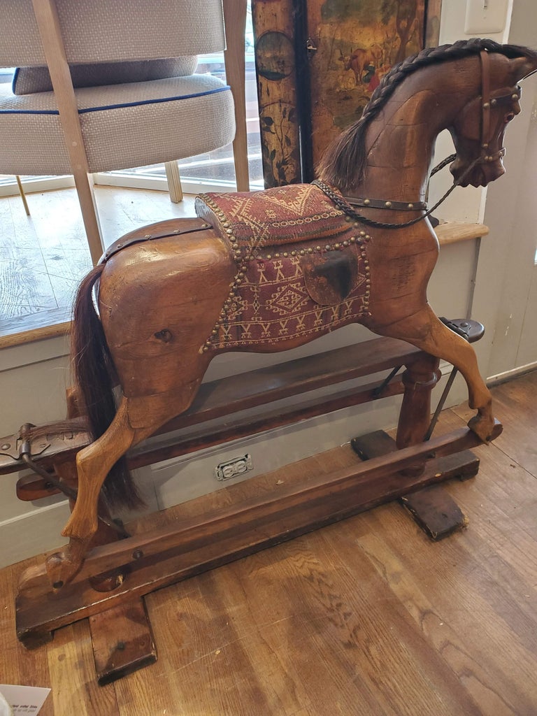 This beautiful 19th century English Rocking Horse has some stories to tell. Made of carved beech and pine woods polished to a rich honey color with upholstered saddle over turned frame, this horse will look wonderful in a nursery or child's