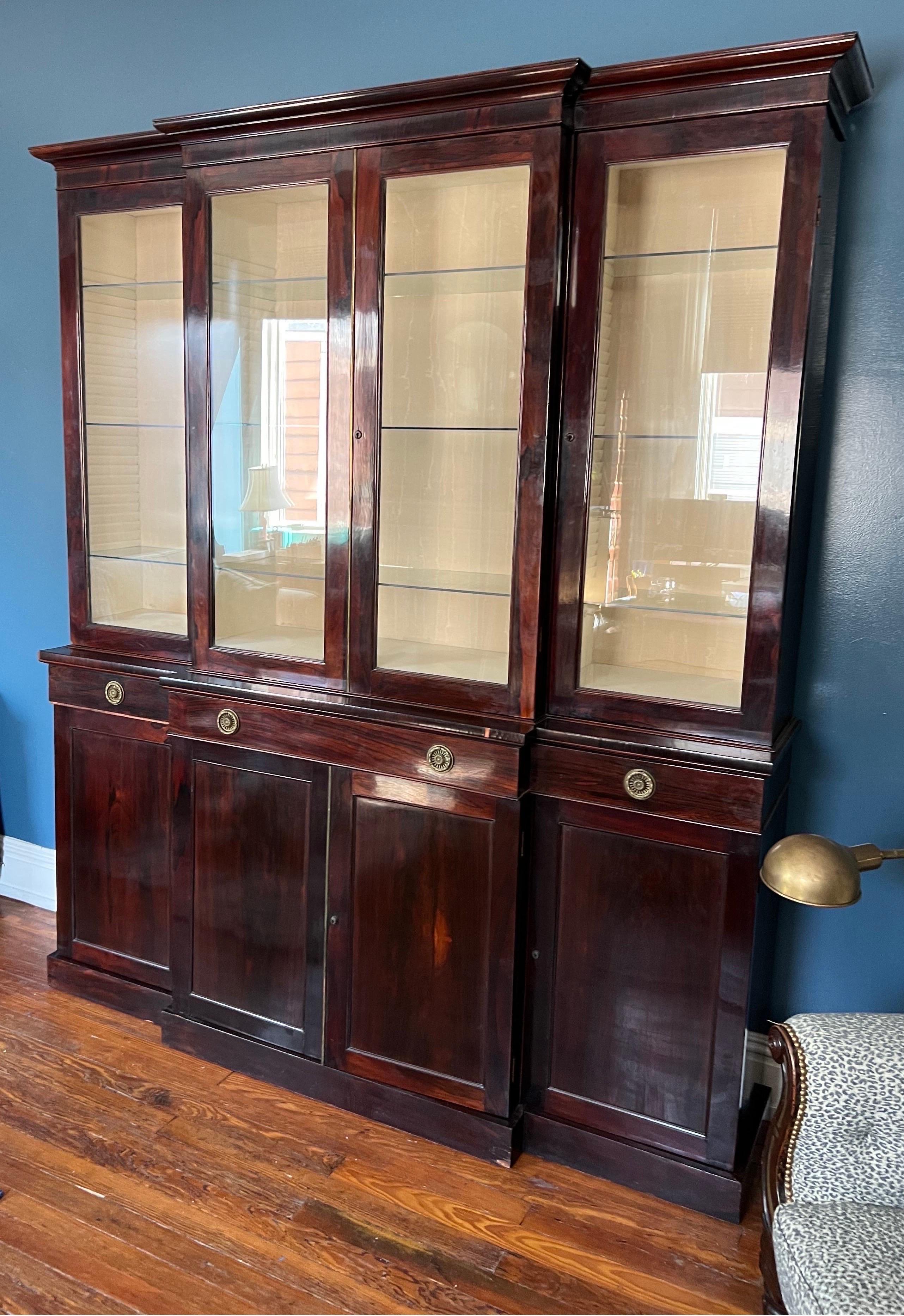 Fine 19th century English regency period Rosewood breakfront bookcase. “Plain and neat” but refined with details such as row of horizontal shelves hidden by the bottom rail of the glazed doors on top, finely casted pulls and brass molding down the
