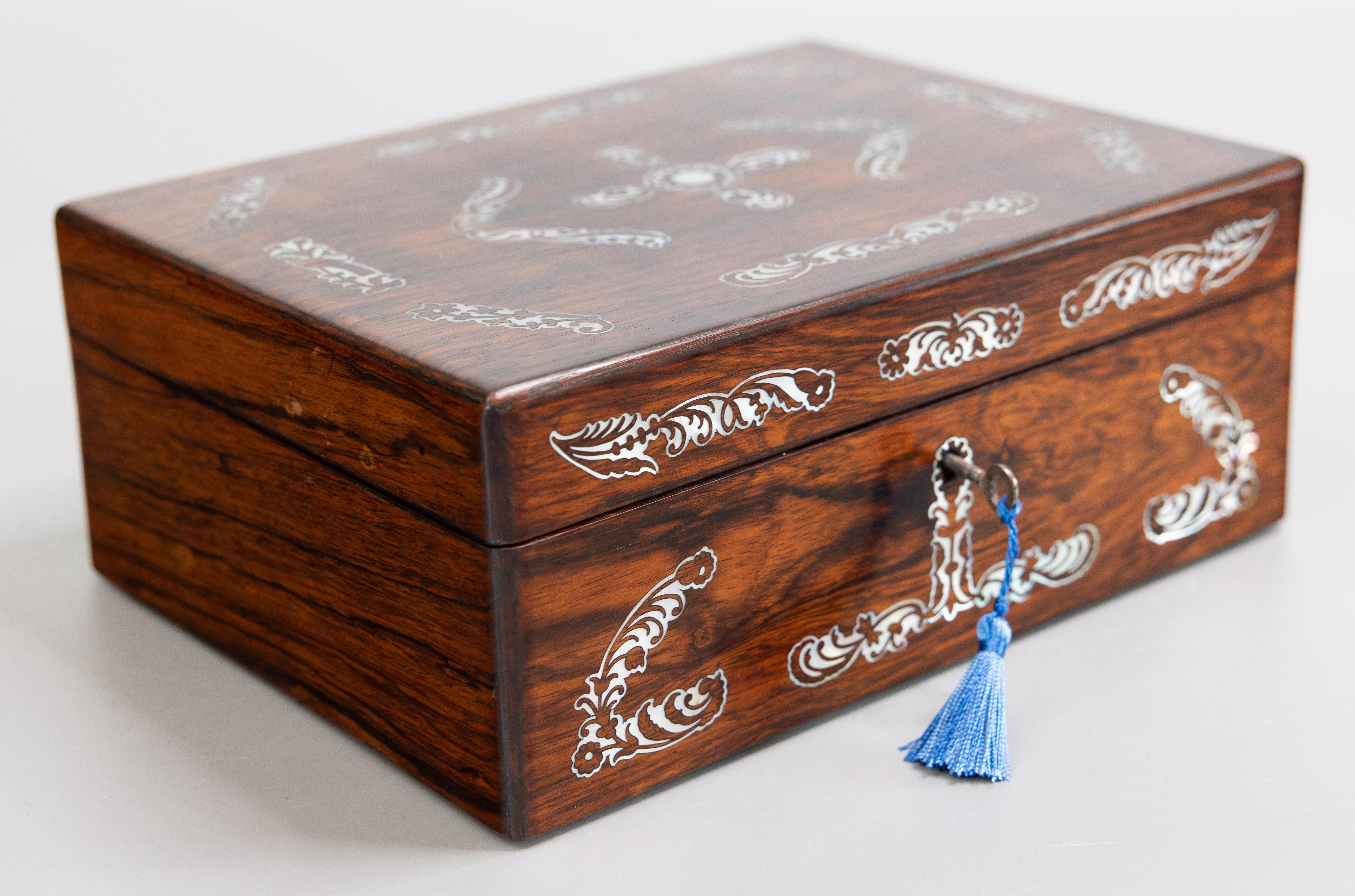 A superb antique Victorian English rosewood jewellery box with fitted interior, a removable inner jewellery tray, and fully working lock and key, circa 1850. The lid and front of this exquisite box are decorated with finely inlaid mother of pearl