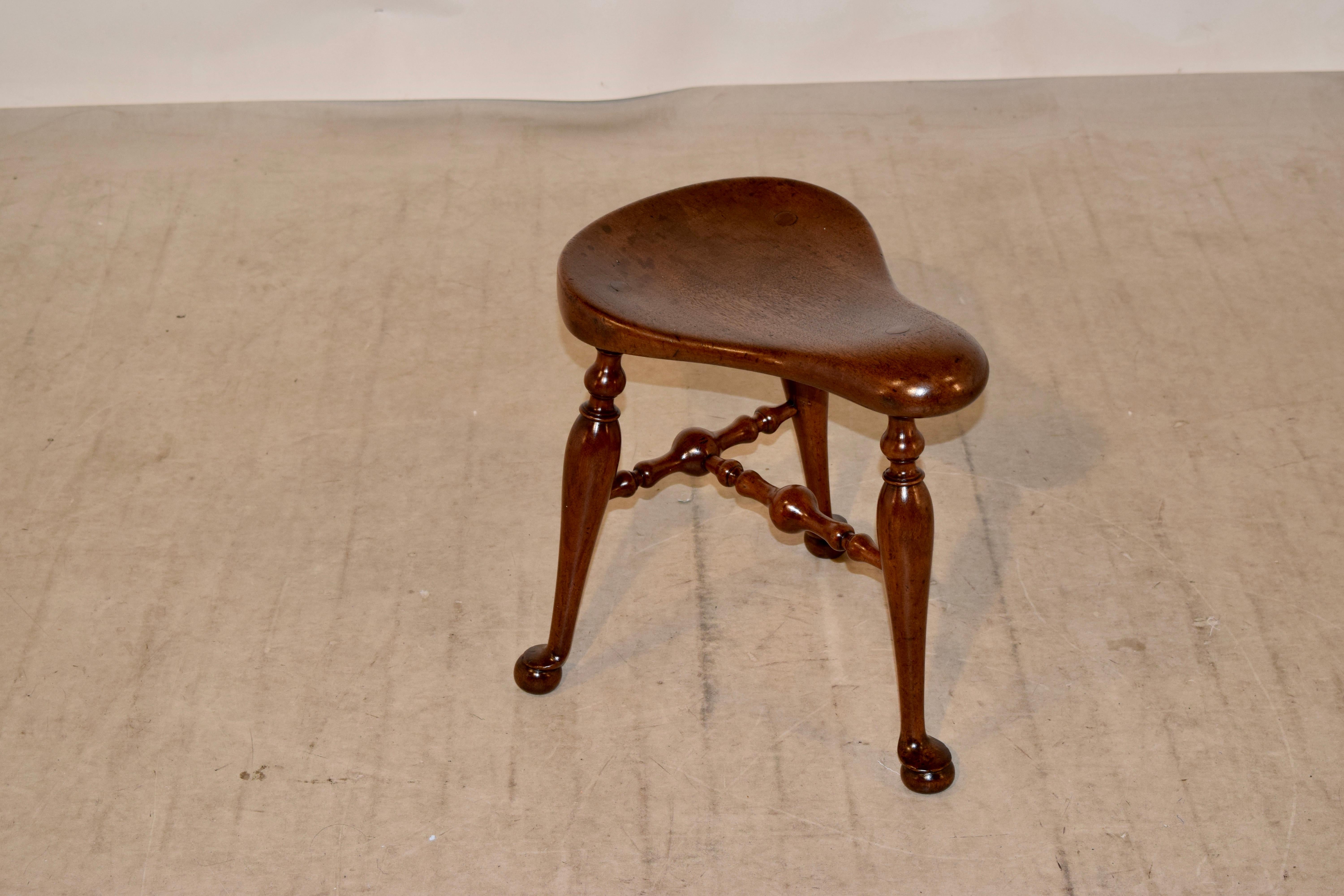 A fine quality late 19th century walnut saddle seat stool from England. This unusual stool has a shaped saddle seat with turned stretchers and terminating with pad and ball feet. Underneath the seat is a stamped registration mark as follows: Reg no: