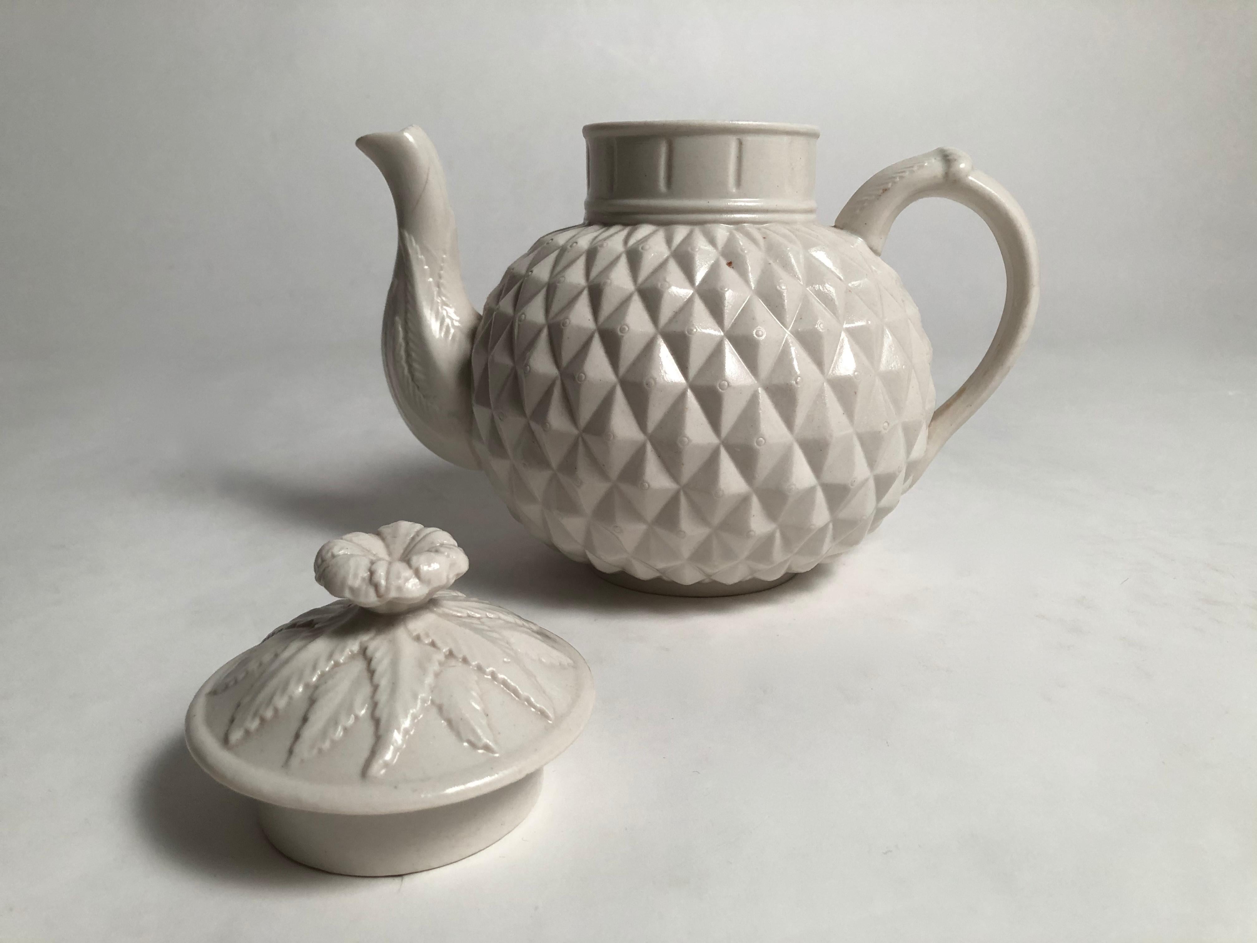 A 19th century English salt glazed stoneware teapot in the form of a pineapple, the lid and finial, spout and handle decorated with pineapple leaves, the globular shaped body with crisply modeled pineapple facets. This is a whimsical, wonderfully