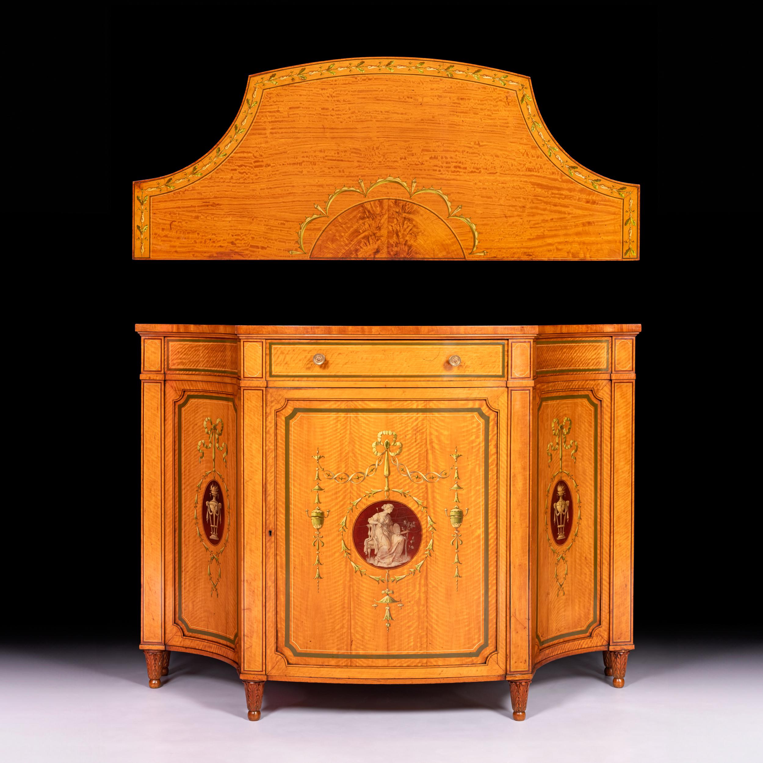 Armario auxiliar de estilo neoclásico del siglo XIX, de madera de satén, con forma de arco en arco, que se eleva sobre seis elegantes patas talladas, con puerta central en arco.  centrado por una escena neoclásica con realces florales que se abre